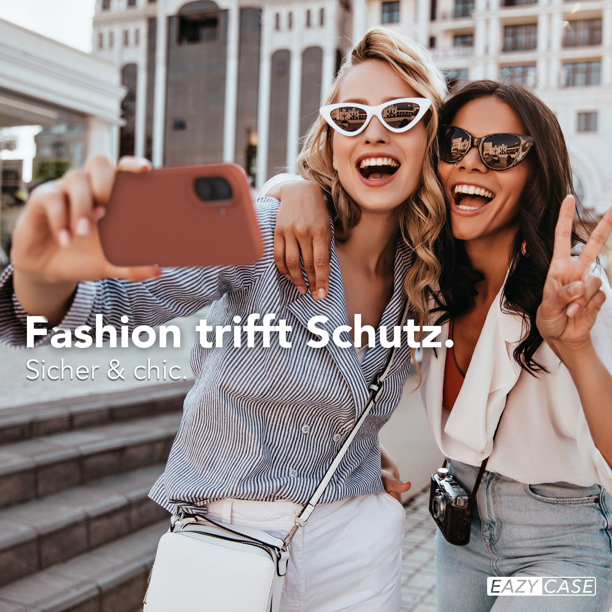 Zwei lachende Frauen machen ein Selfie mit einem Handy. Sie tragen Sonnenbrillen.