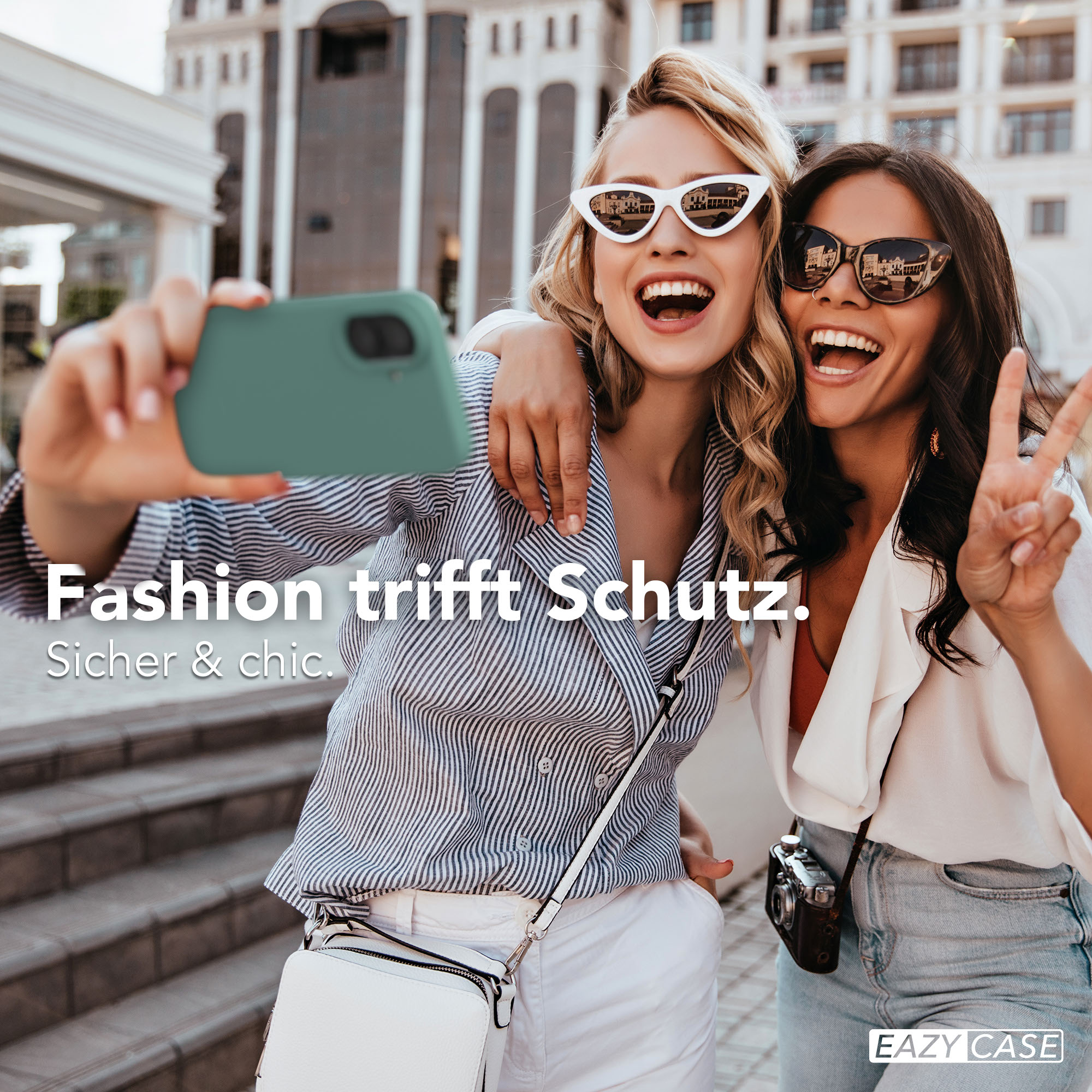 Zwei Frauen machen ein Selfie, eine hält ein Handy, die andere zeigt V-Zeichen.
