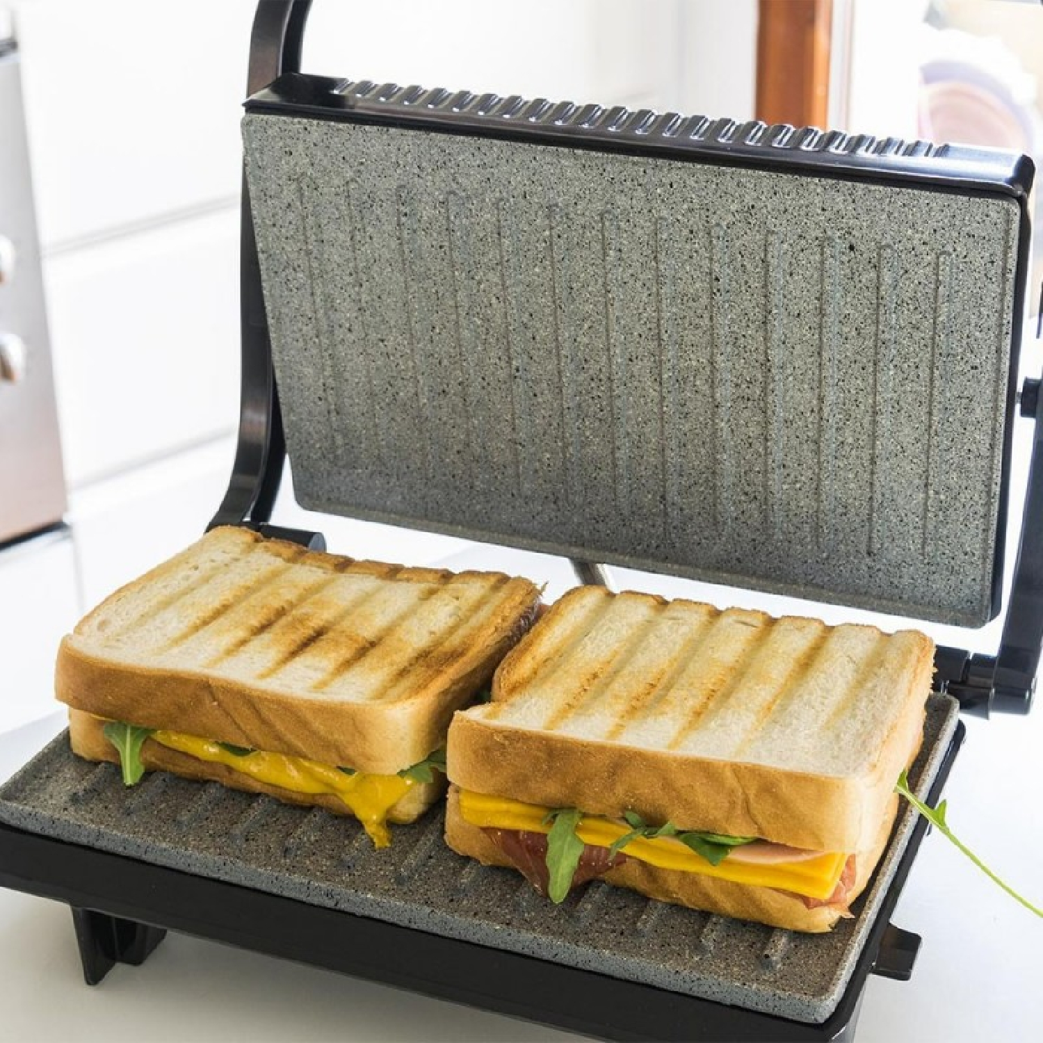 Due panini al formaggio e insalata vengono cotti in una griglia a contatto aperta.