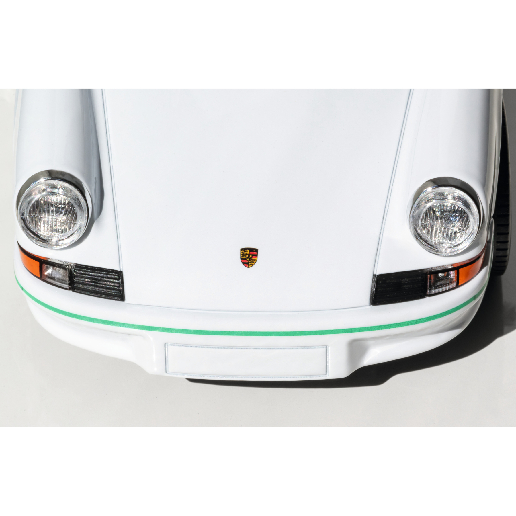 Weiße Porsche-Front mit Scheinwerfern, Emblem und grüner Zierlinie.