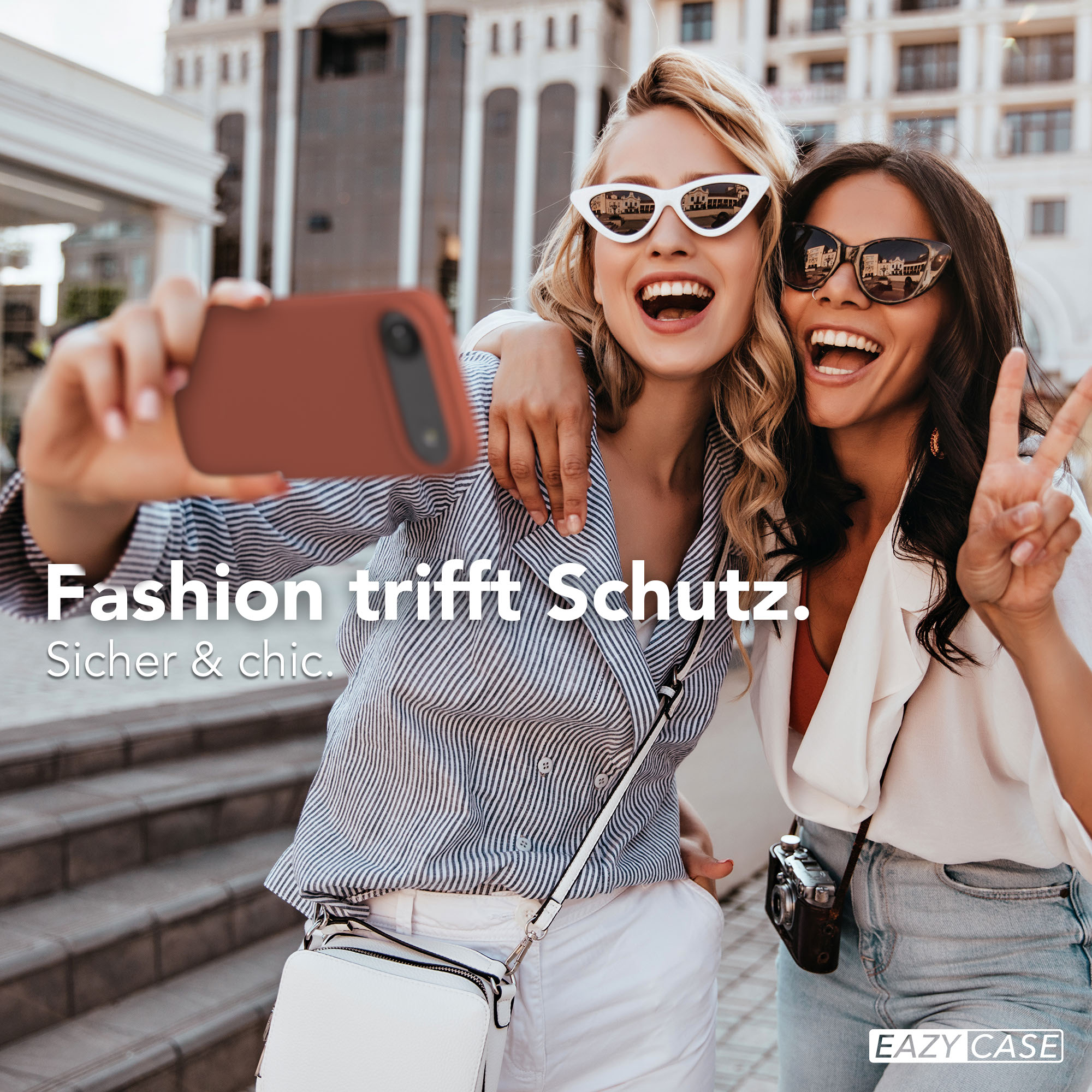 Zwei Frauen machen ein Selfie vor einer modernen Gebäudefassade.