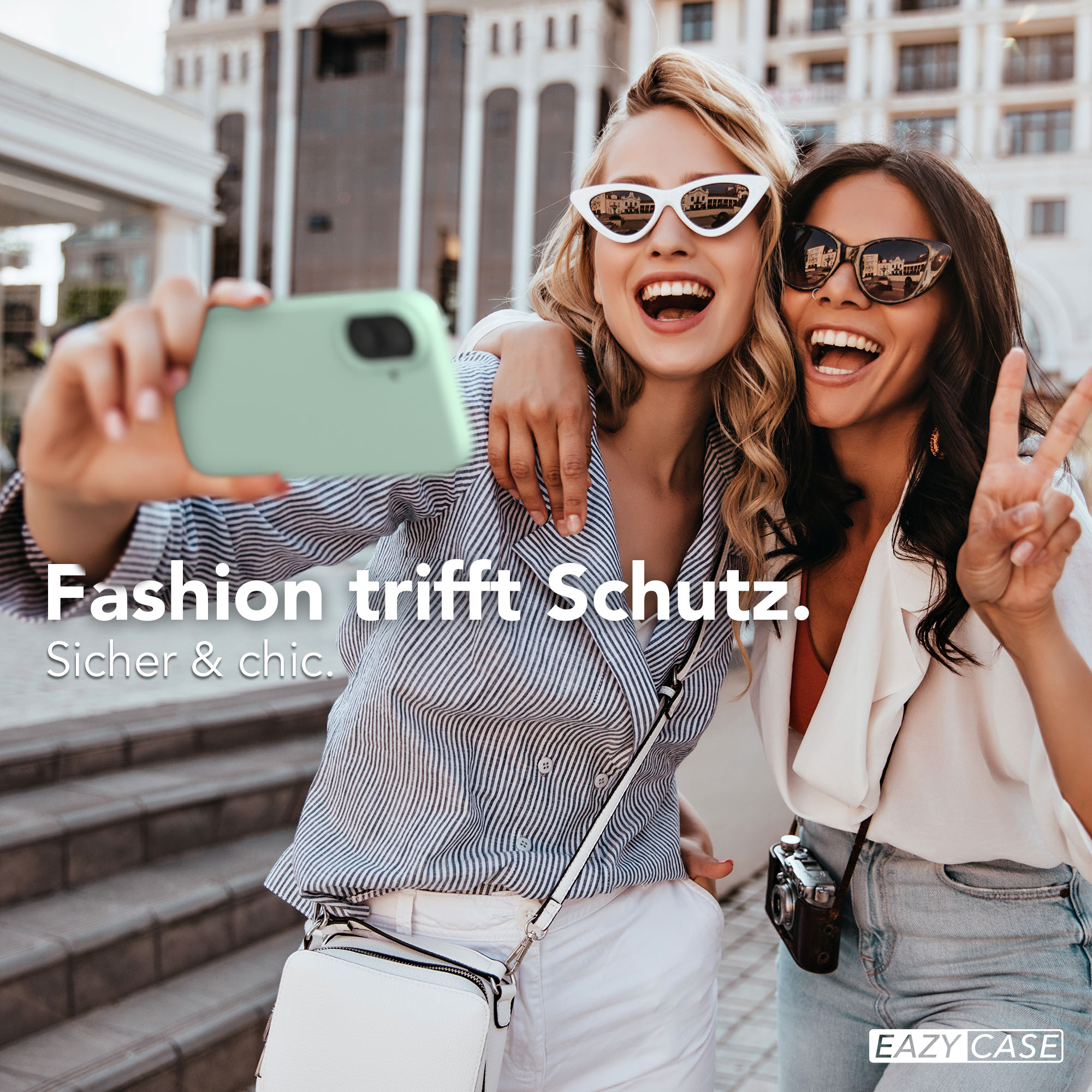 Zwei lachende Frauen machen ein Selfie mit einem Handy. Eine hält das Handy, die andere zeigt Friedenszeichen.