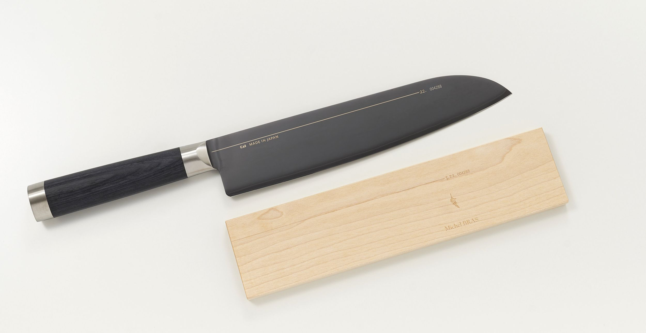 Ein schwarzes Küchenmesser mit Holzgriff liegt neben einem Holzbrett.