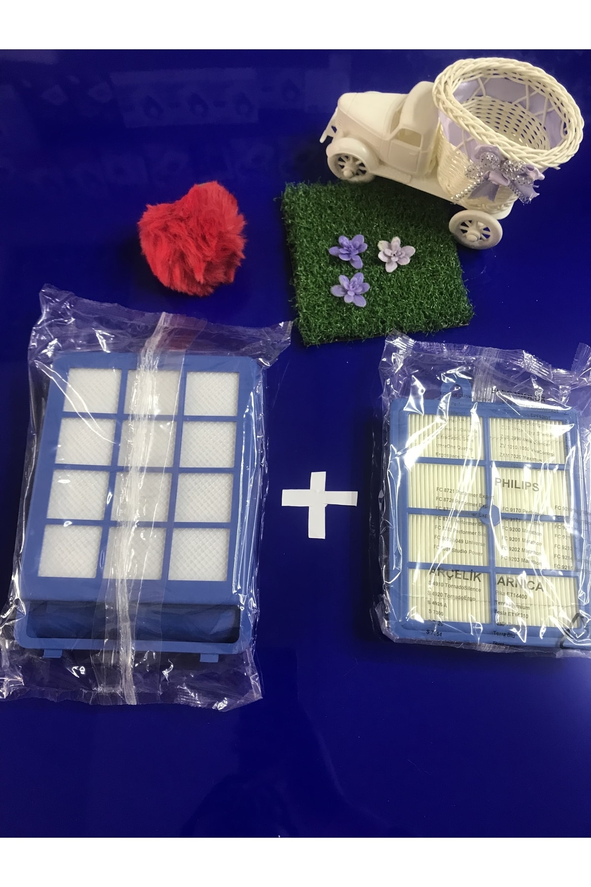 Paketlenmiş iki elektrikli süpürge filtresi, kırmızı kalp ve çiçekli yeşil çim alan.