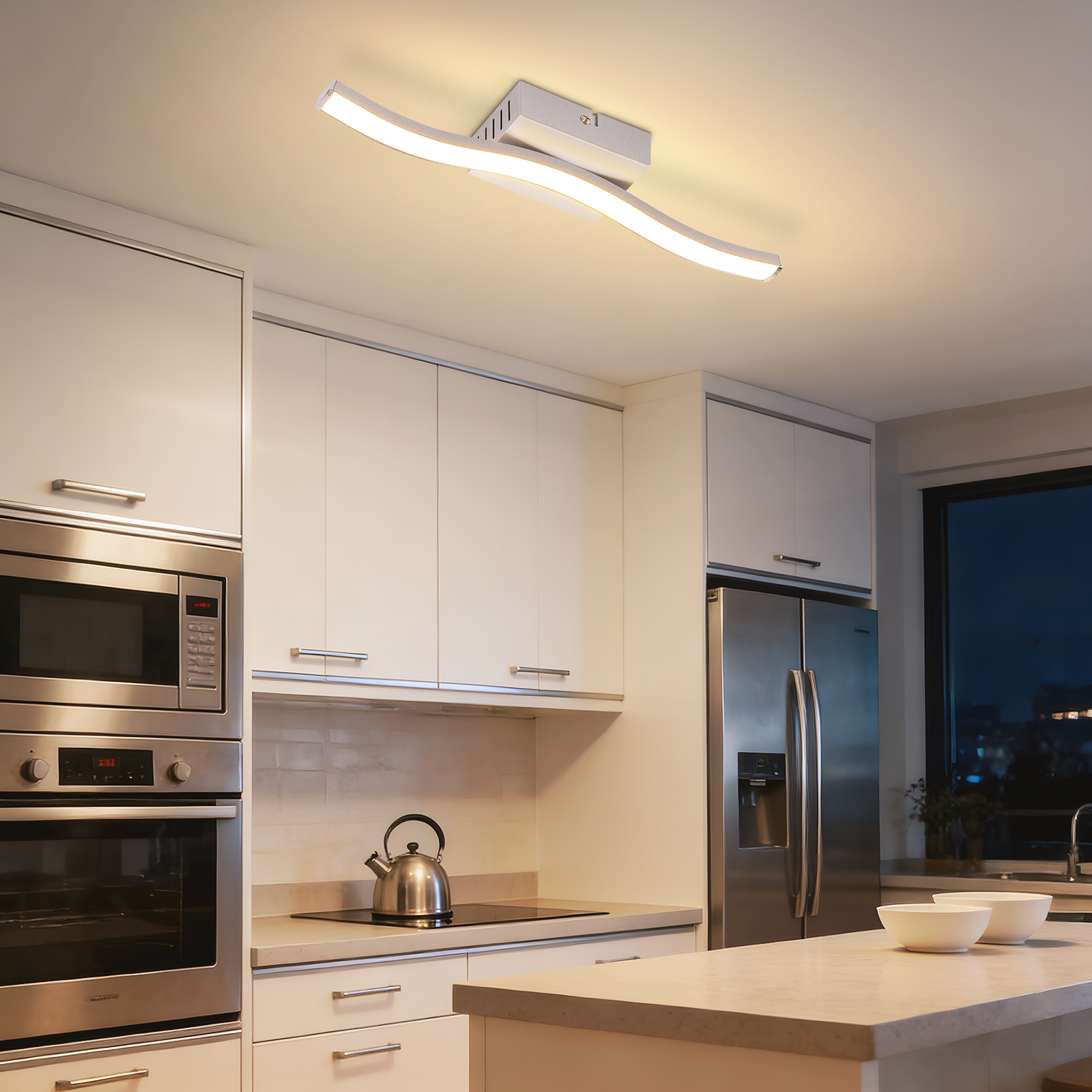Cucina moderna con plafoniera, elettrodomestici in acciaio inox e vista esterna.