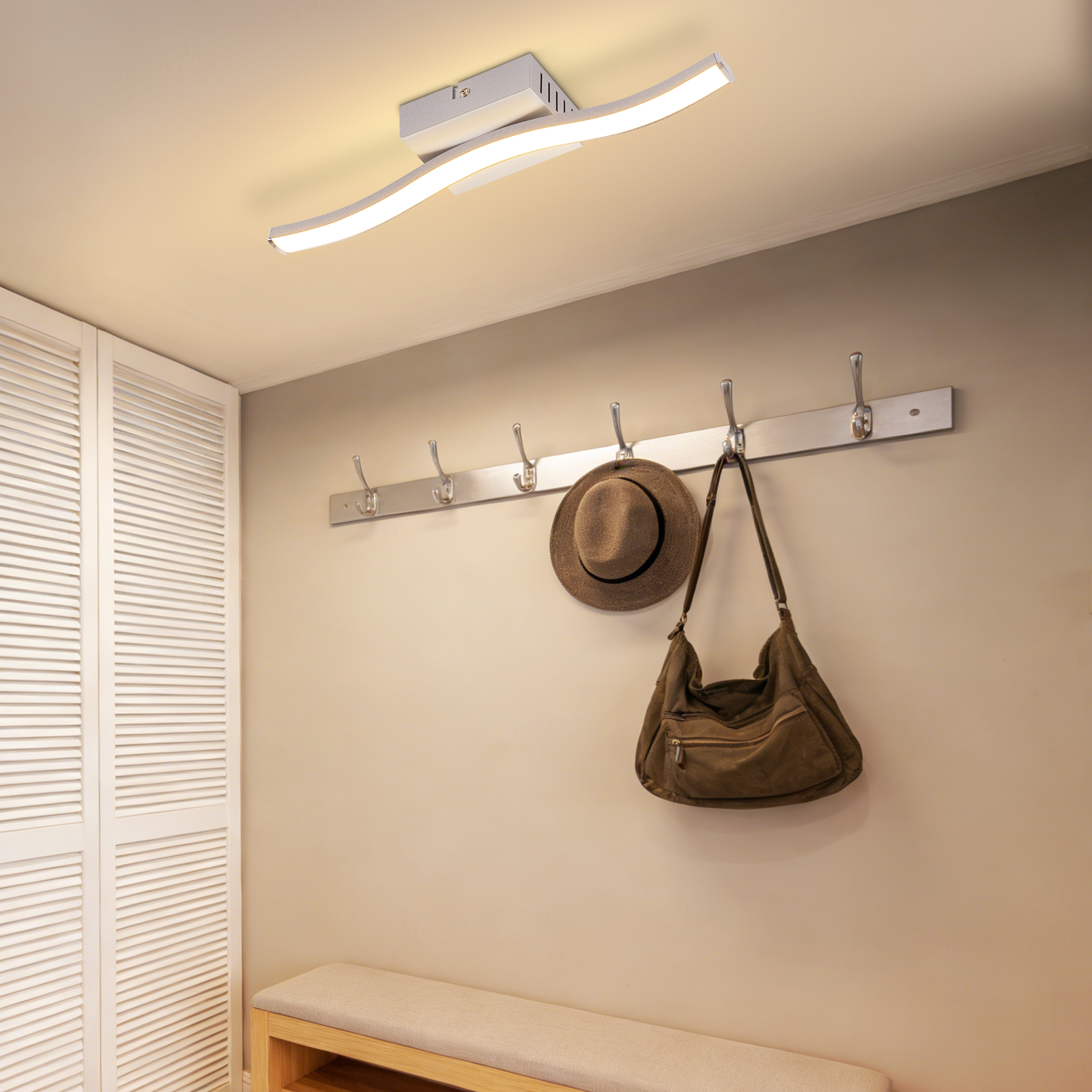 Plafoniera moderna dal design ondulato sopra un attaccapanni con cappello e borsa.