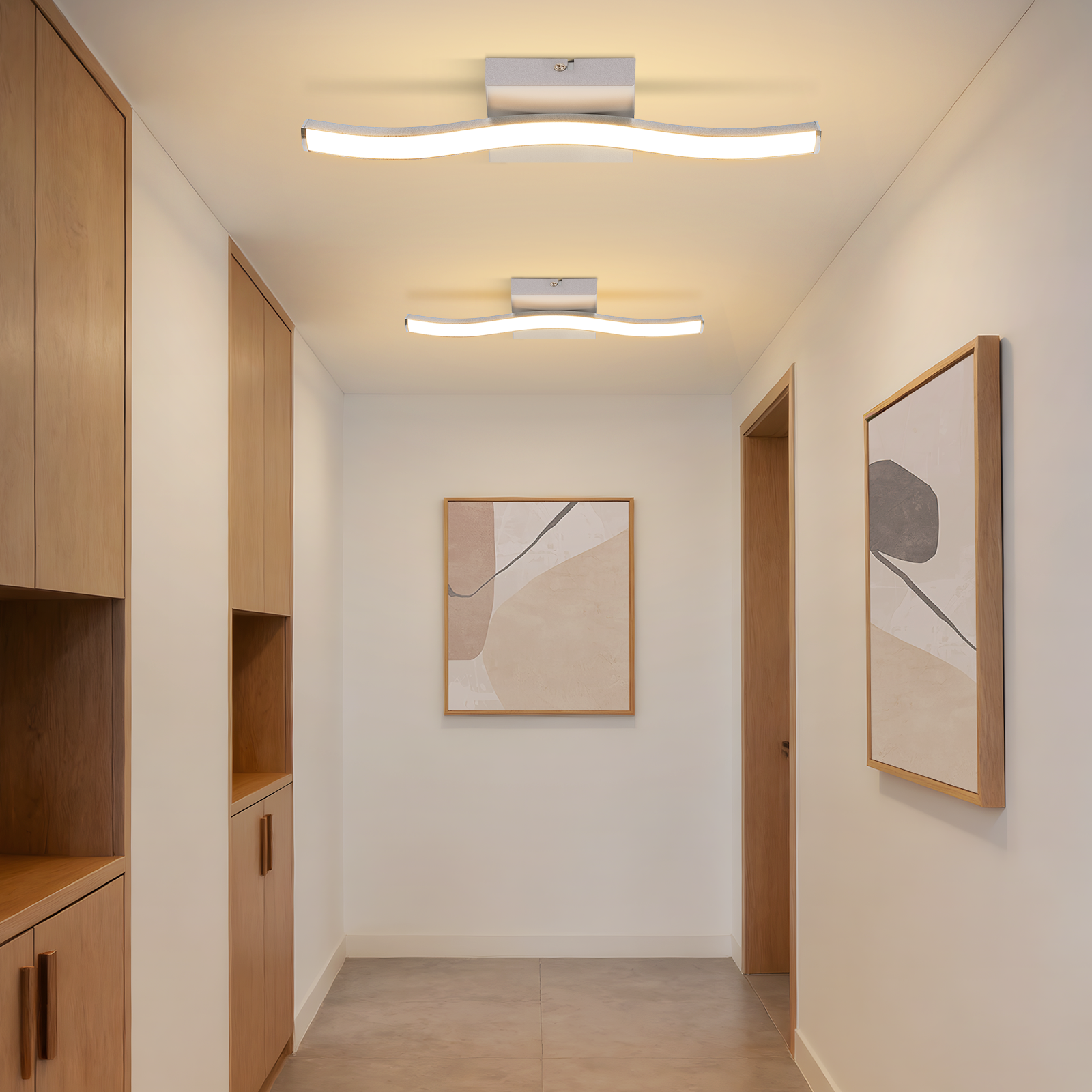 Un corridoio con armadi in legno, due lampade da soffitto curve e arte astratta.