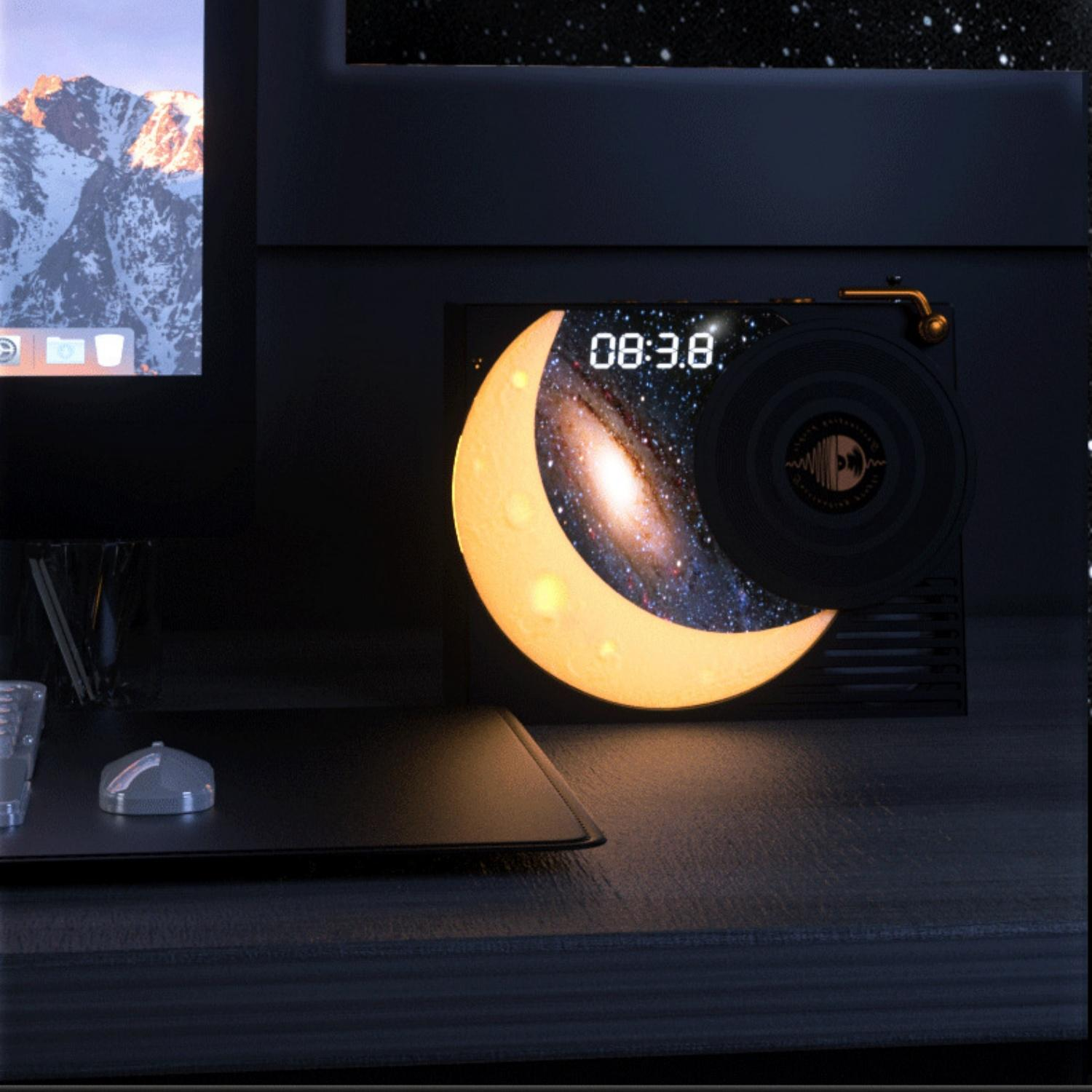 Eine Sichelmondlampe mit einer Galaxie im Inneren zeigt 08:38. Eine Platte liegt auf einem schwarzen Gerät.