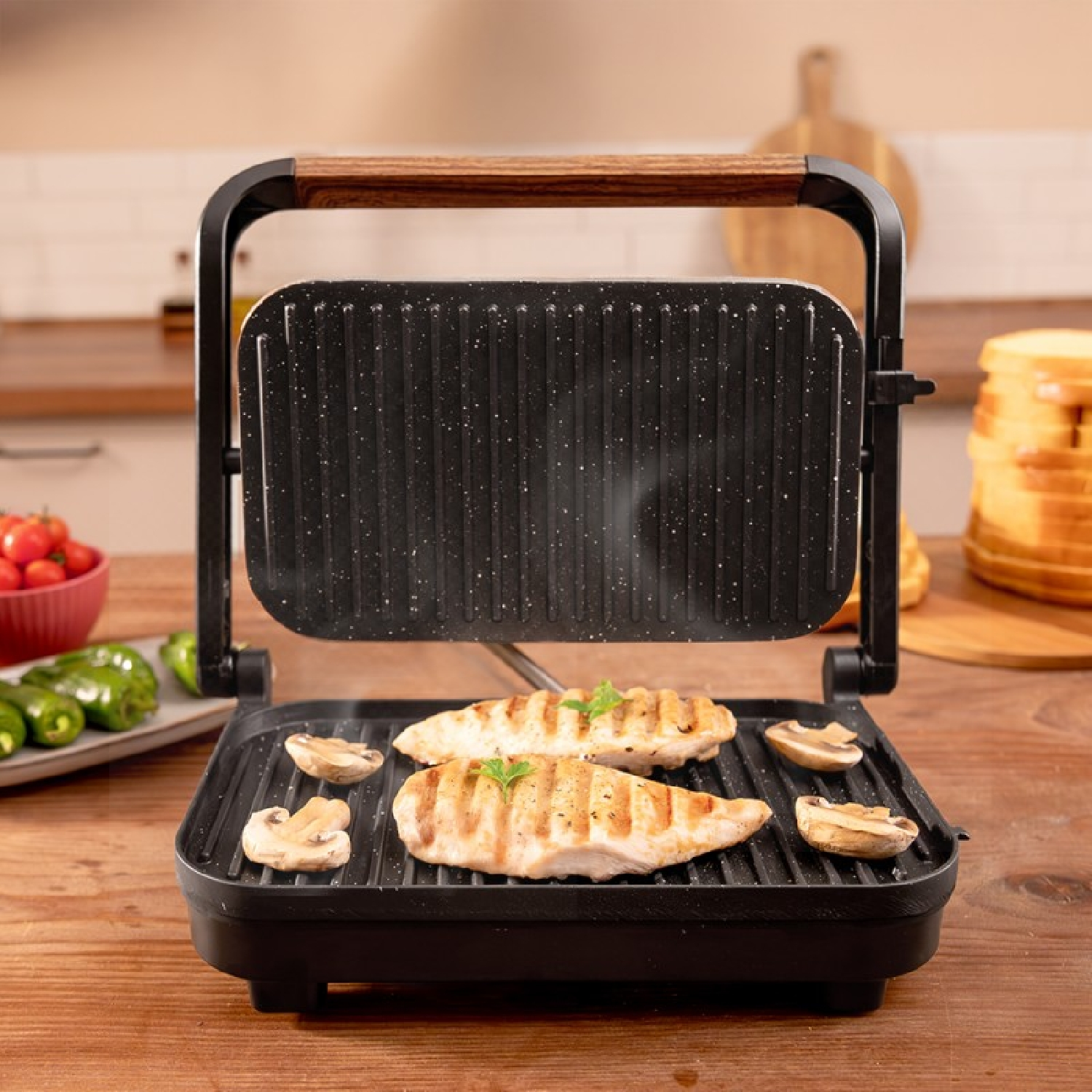 Dos filetes de pechuga de pollo y champiñones se asan en una parrilla con mango de madera.