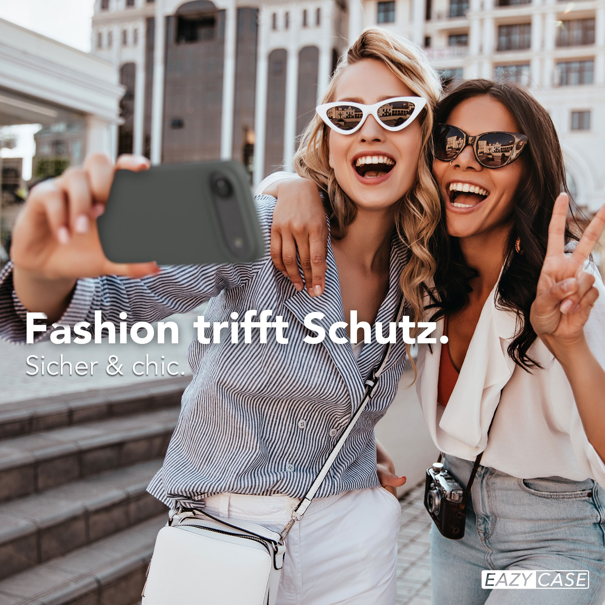 Zwei Frauen machen ein Selfie vor einem Gebäude. Eine hält das Handy.