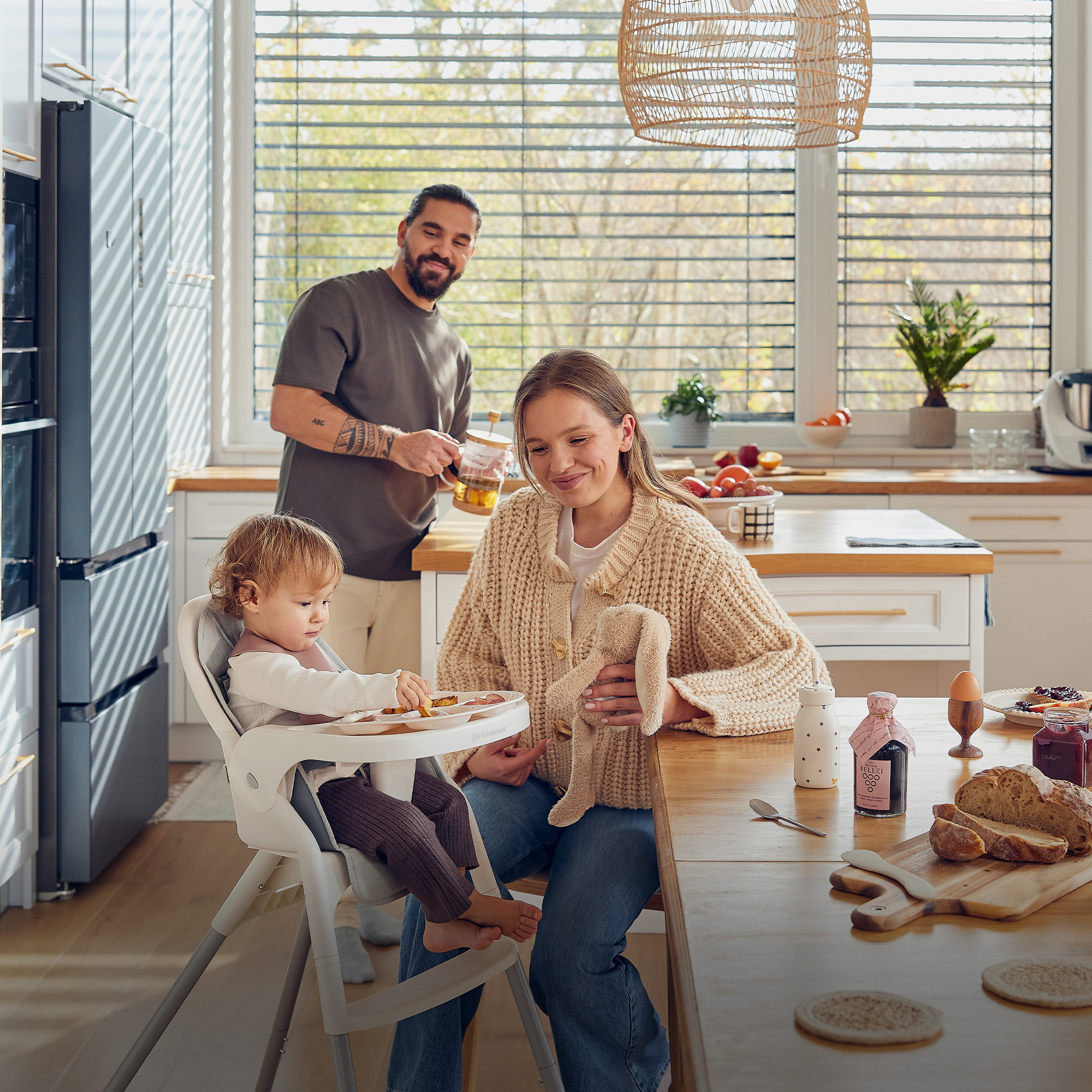 Familie beim Frühstück in der Küche, Kind sitzt im Hochstuhl.