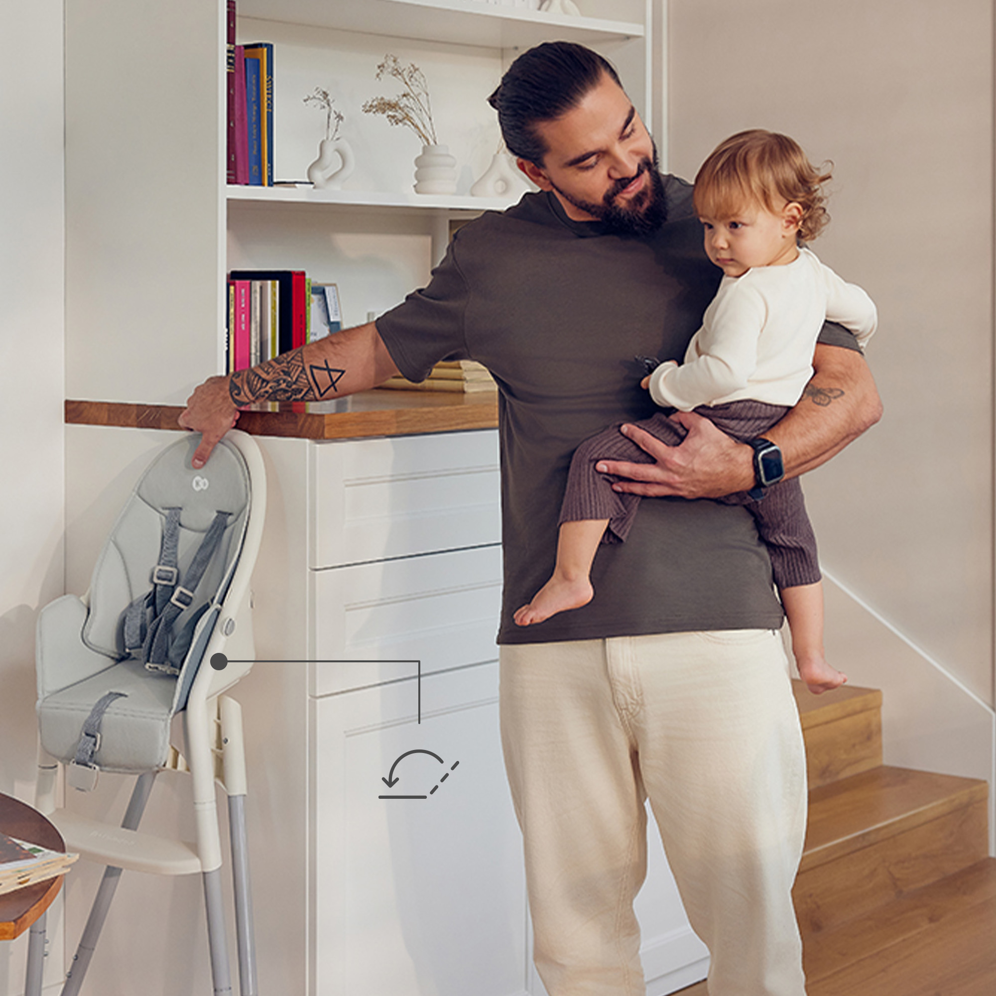 Ein Mann hält ein Baby in einem modernen Zuhause mit einem Hochstuhl.