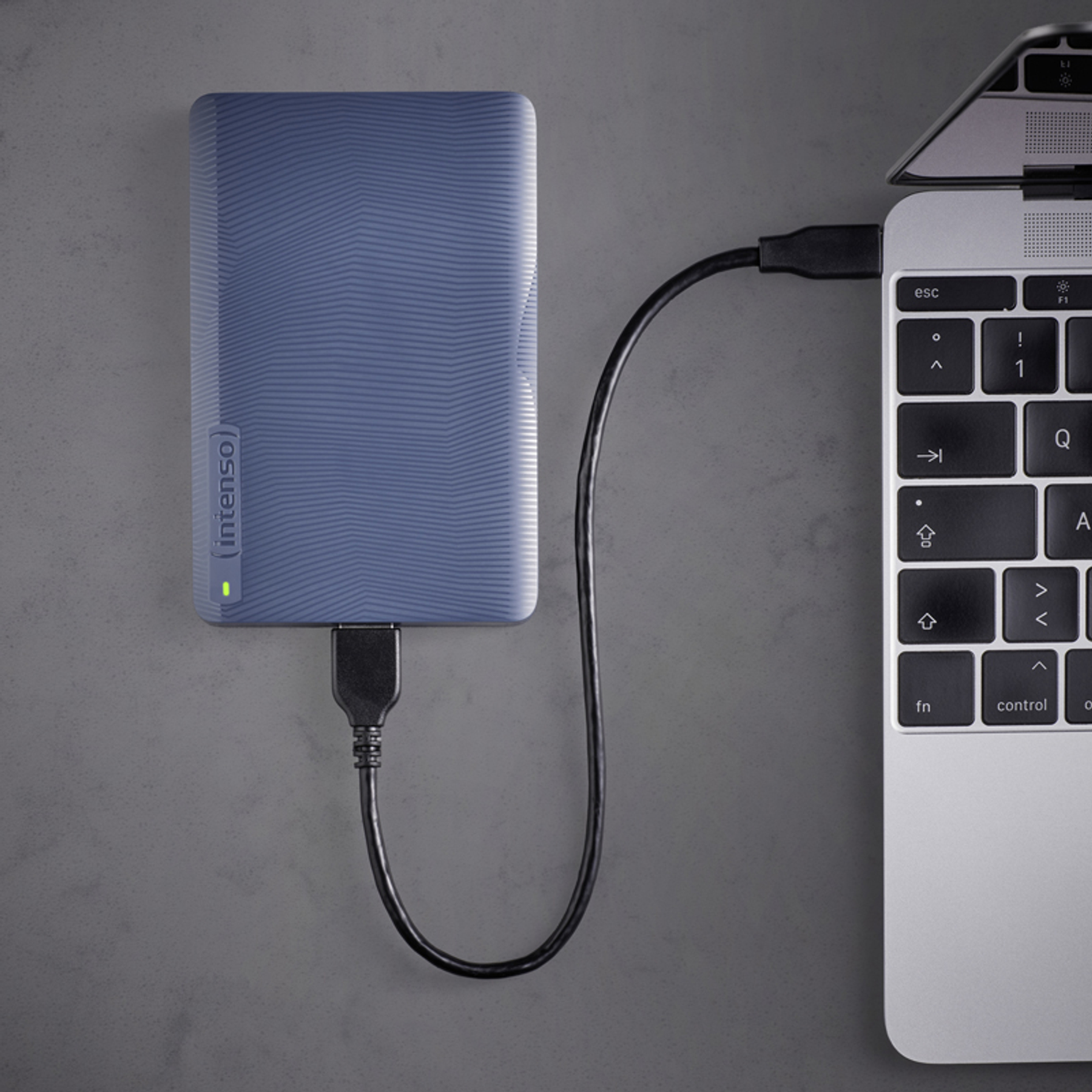 Ein blaues externes Laufwerk ist über ein schwarzes Kabel mit einem Laptop verbunden.