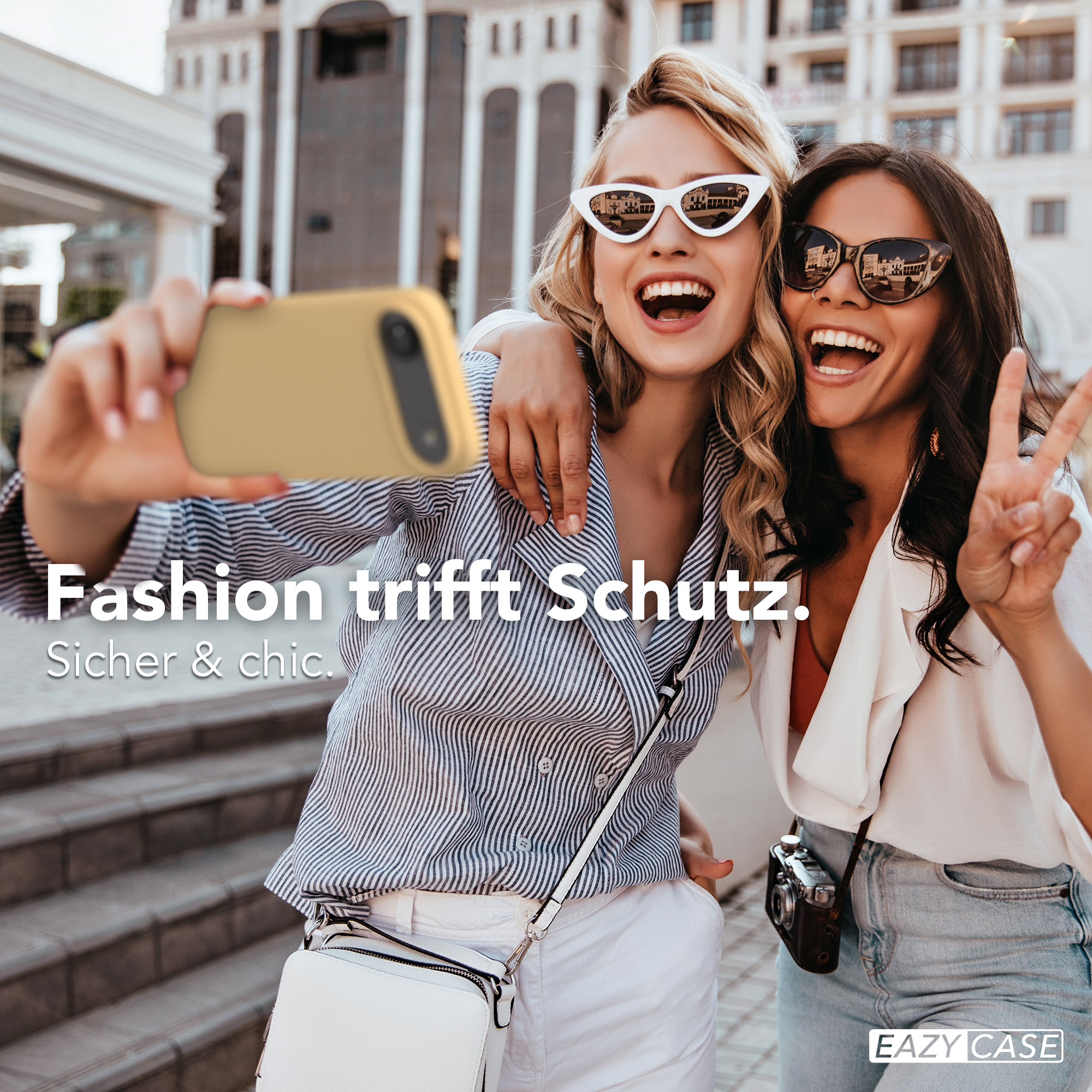Zwei Frauen machen ein Selfie in der Stadt, eine hält ein Handy.