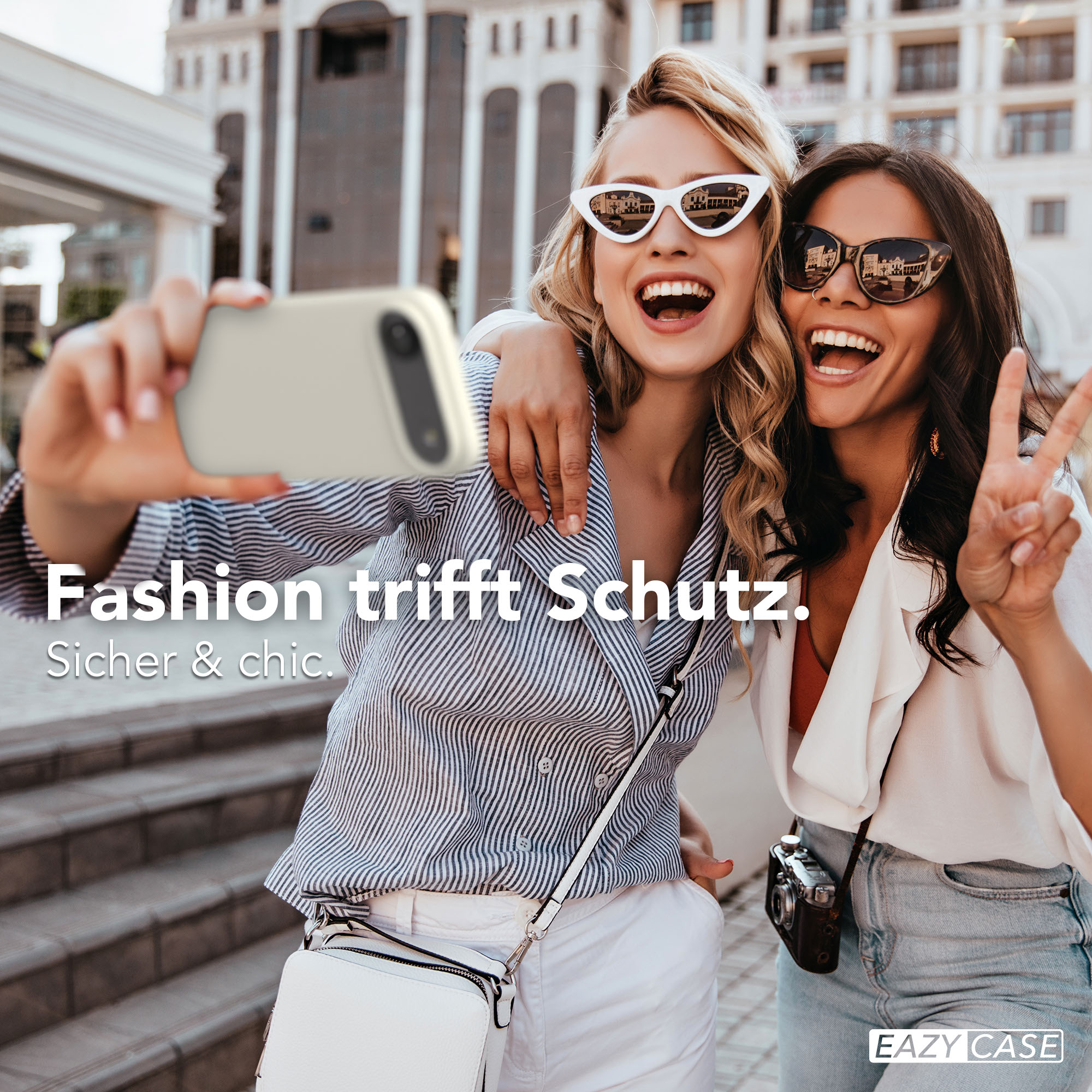 Zwei lachende Frauen machen ein Selfie mit einem Handy, eine winkt mit der Hand.