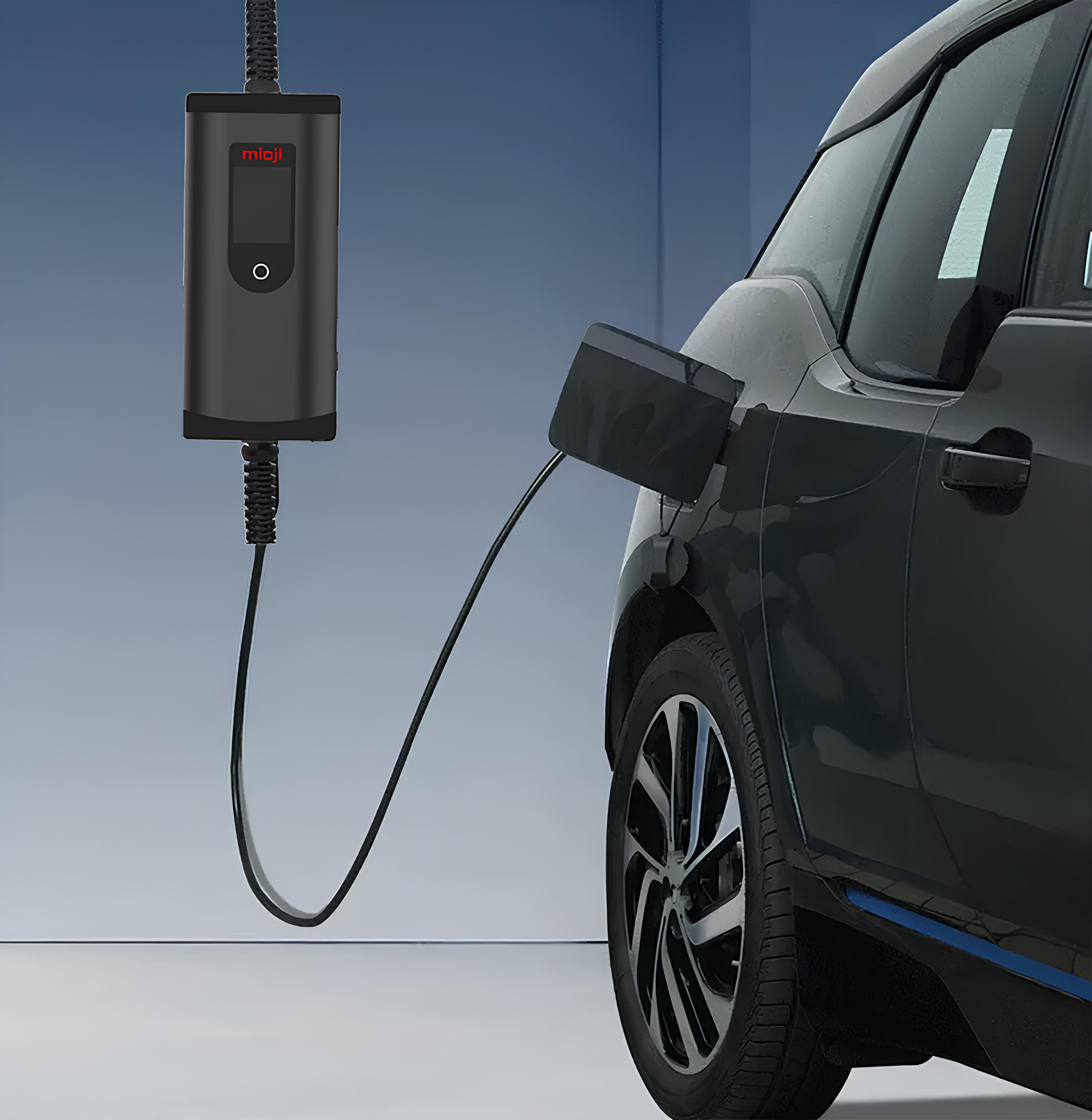 Siyah bir elektrikli otomobil şarj istasyonunda şarj oluyor. Şarj kablosu bağlı.