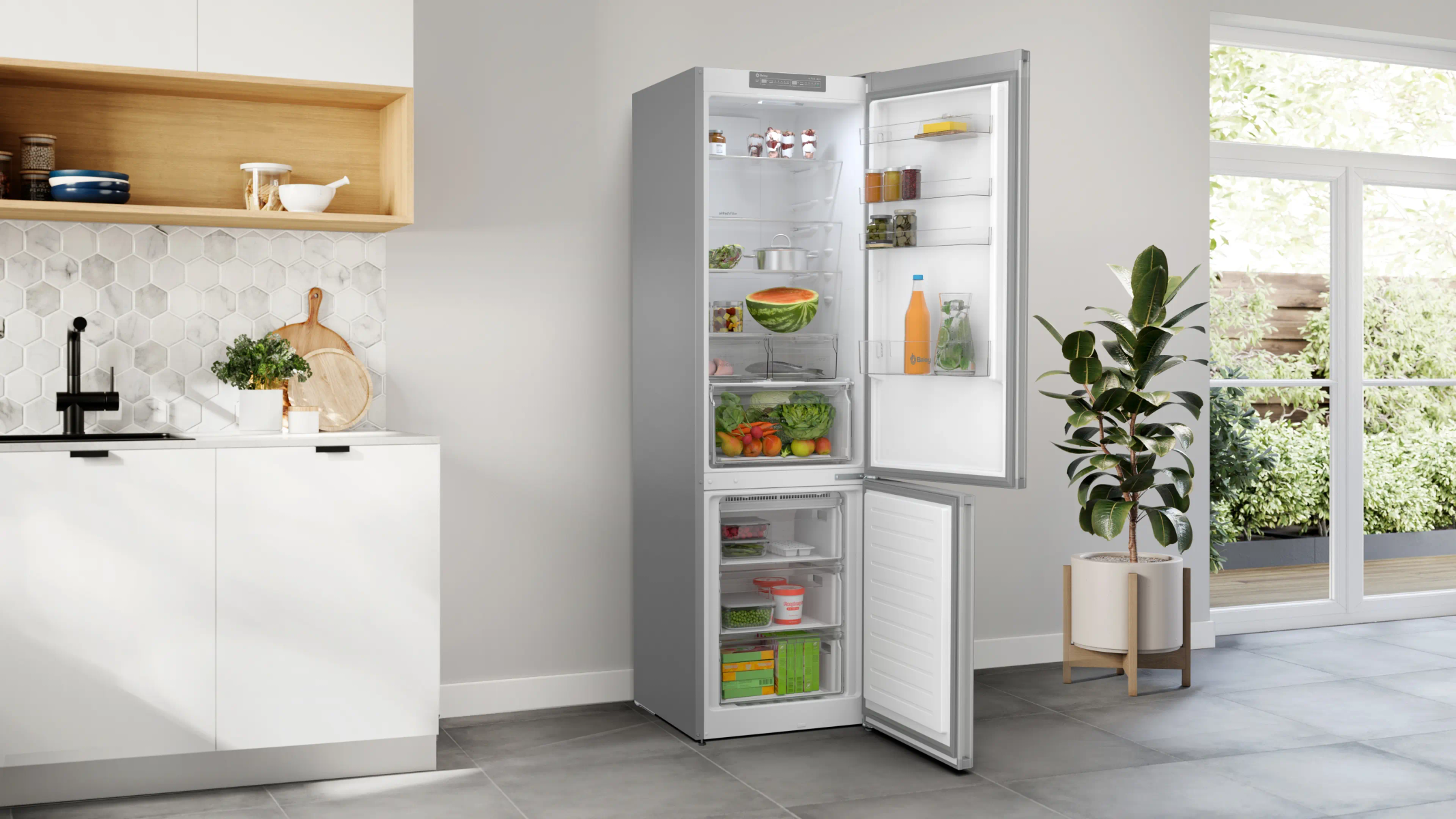 Refrigerador abierto en una cocina con frutas, verduras y bebidas. Una planta está al lado.