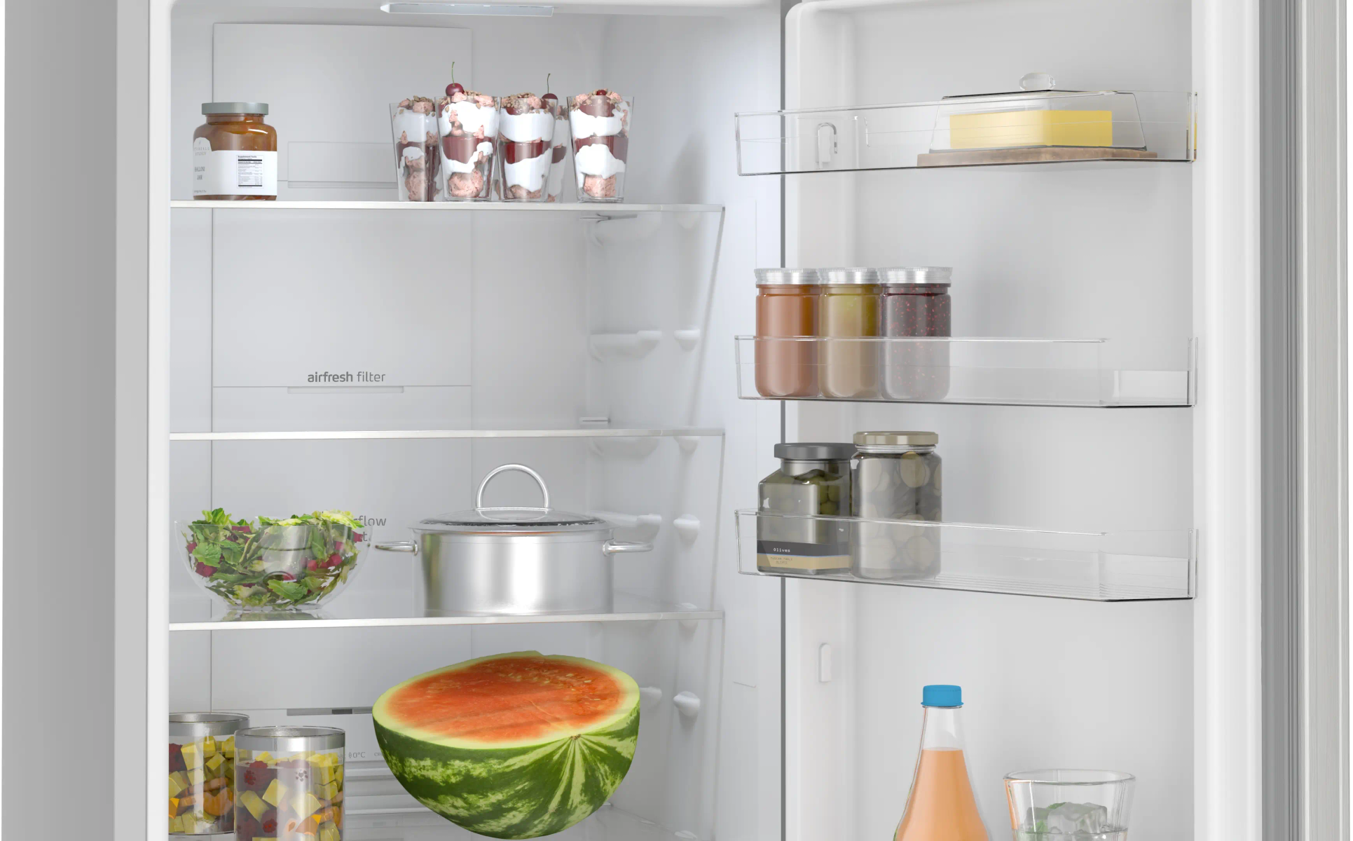 Refrigerador abierto con comida: frascos, postres, ensalada, olla, sandía, bebidas, mantequilla.
