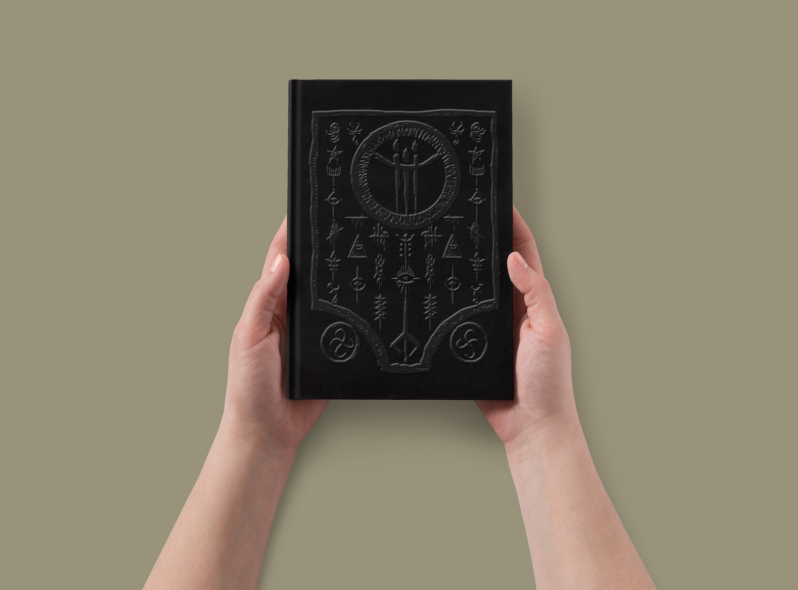 Libro negro con símbolos místicos, sostenido por dos manos.