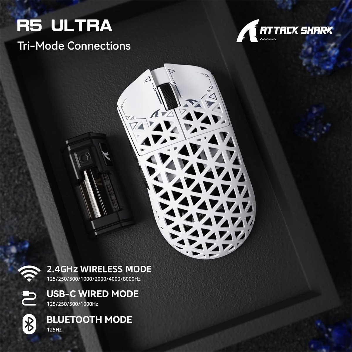 White gaming mouse with honeycomb design and black dongle on a dark surface.