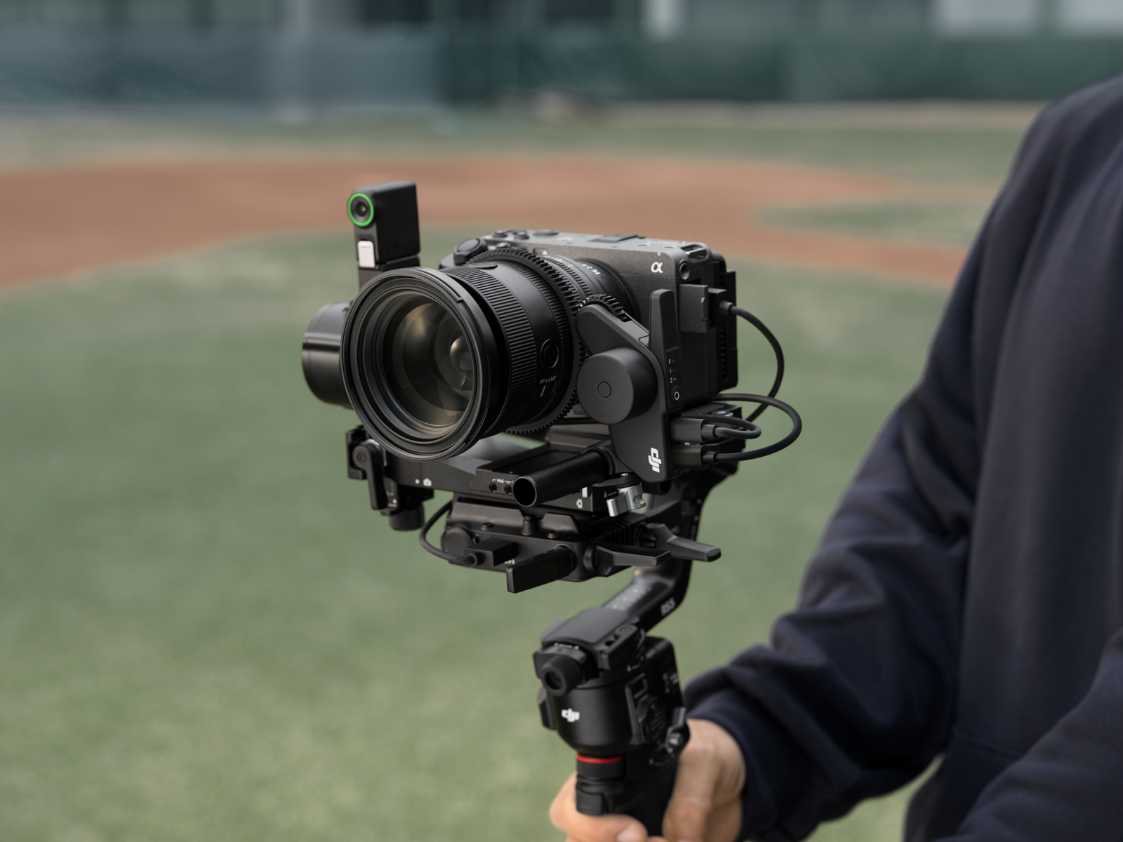 Una fotocamera con obiettivo e gimbal, tenuta da una persona all'aperto.