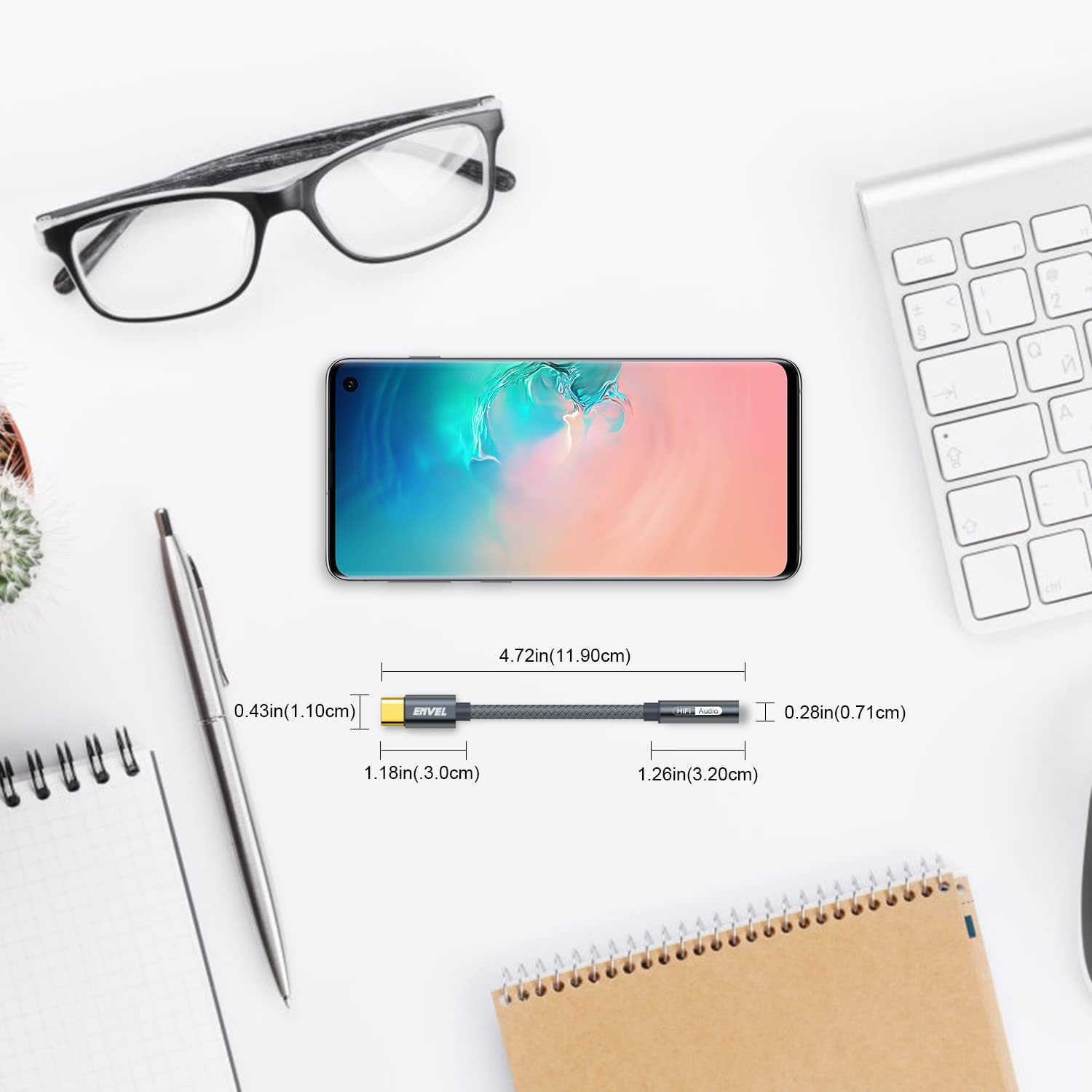 Smartfon, okulary, klawiatura, kabel i notatnik na białym biurku.