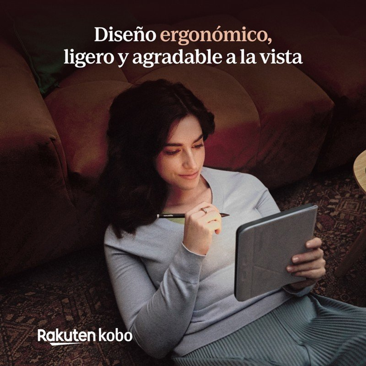 Una donna dai capelli scuri è seduta su un divano, tiene in mano un tablet e uno stilo.