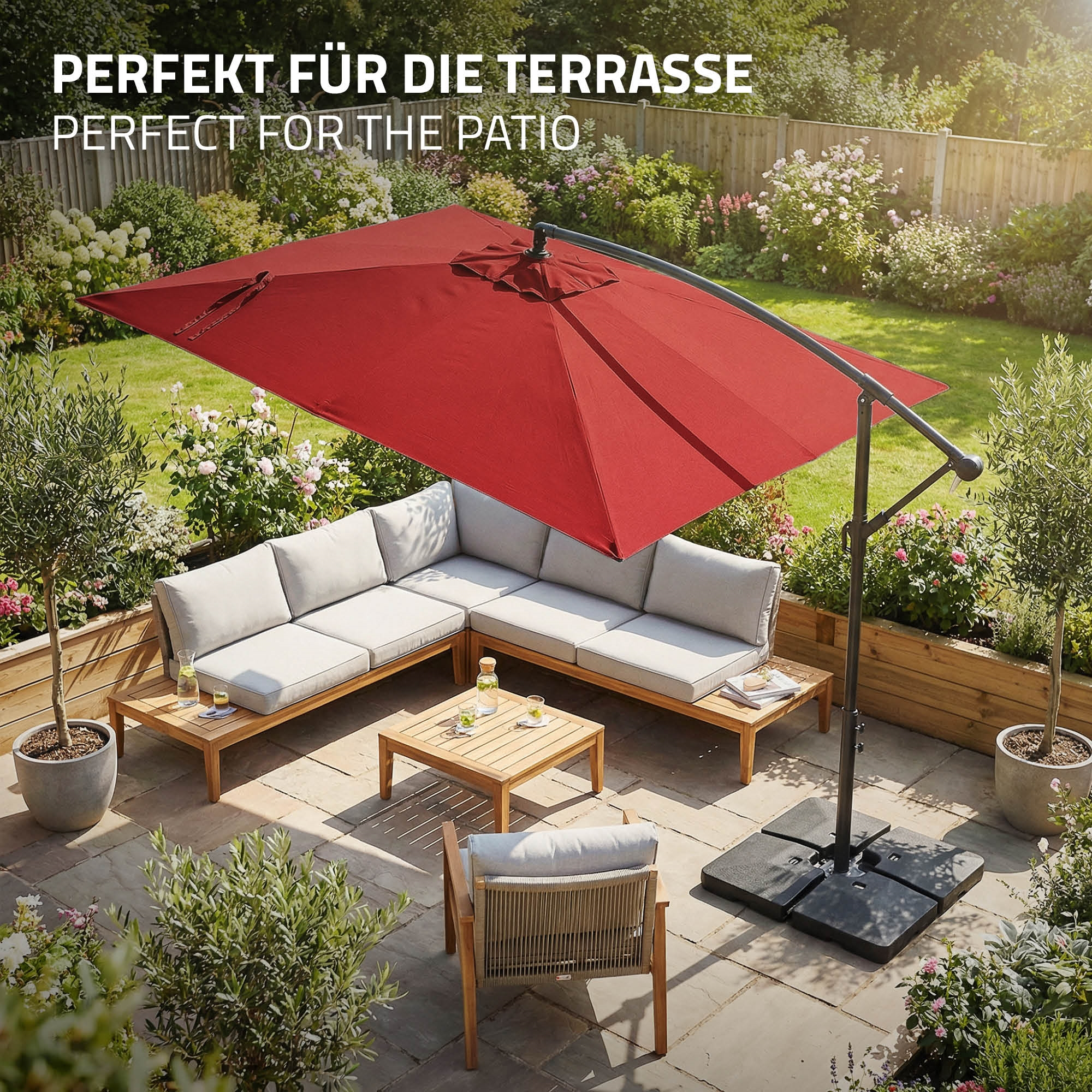 Gartenmöbel mit rotem Sonnenschirm auf einer Steinterrasse mit Blumen.