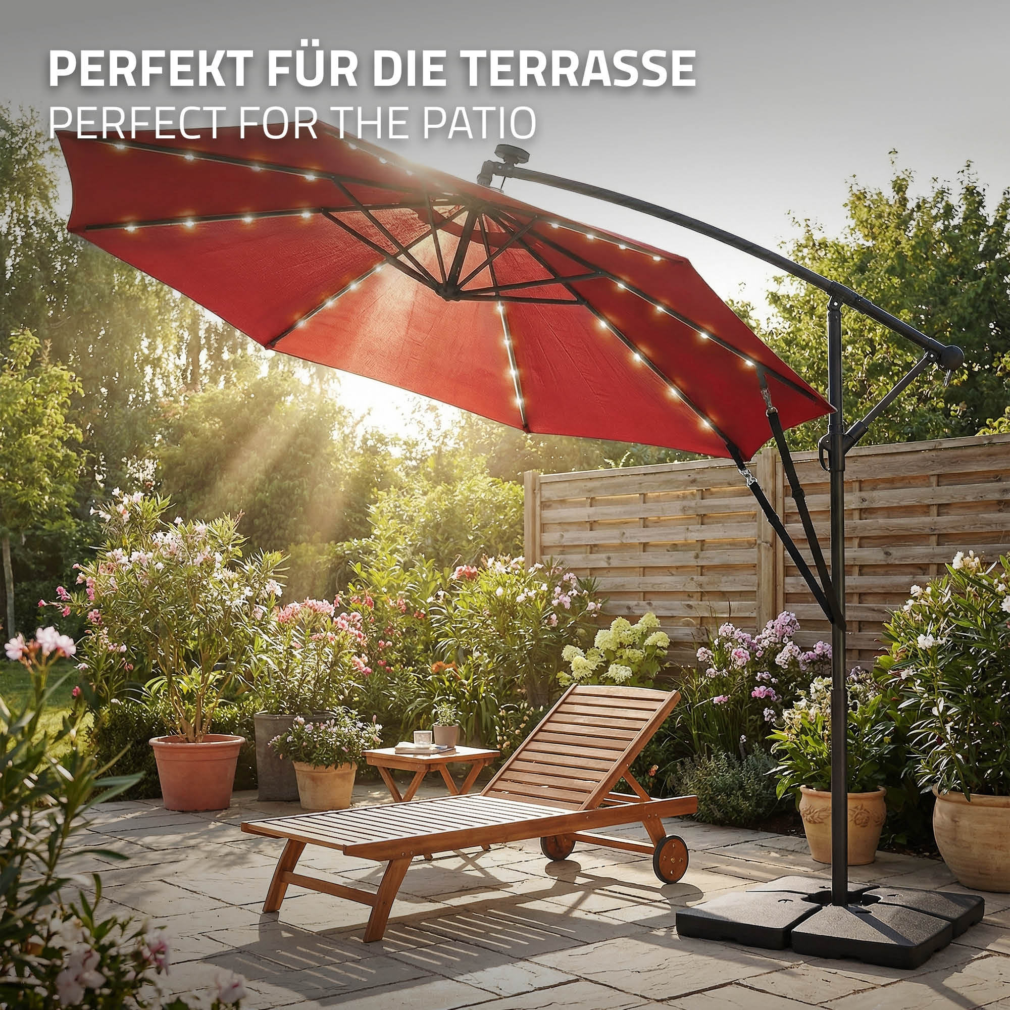 Ein roter Sonnenschirm mit Lichterkette über einem Liegestuhl auf einer Terrasse.