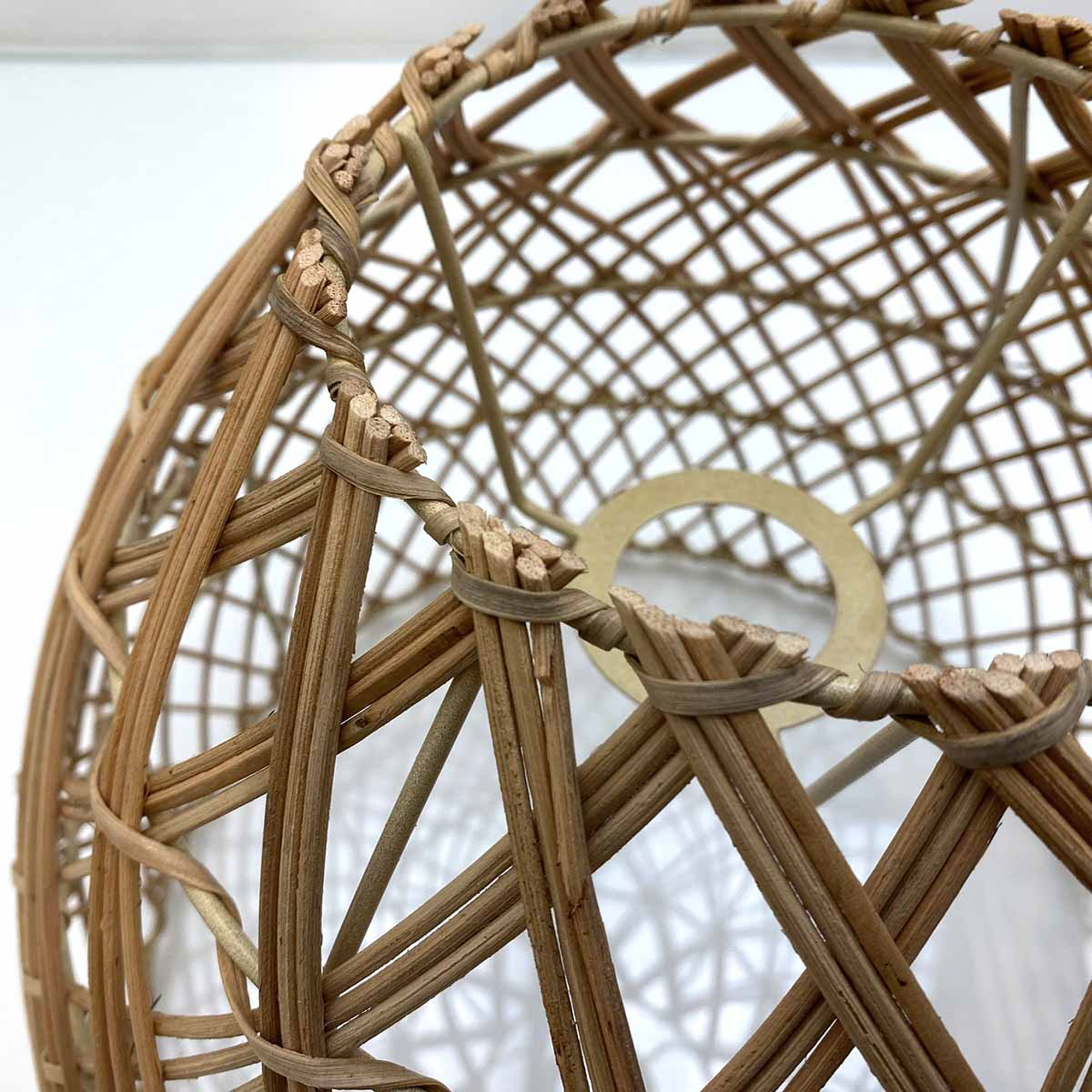 Una pantalla de lámpara en forma de cesta de madera con patrón de red.