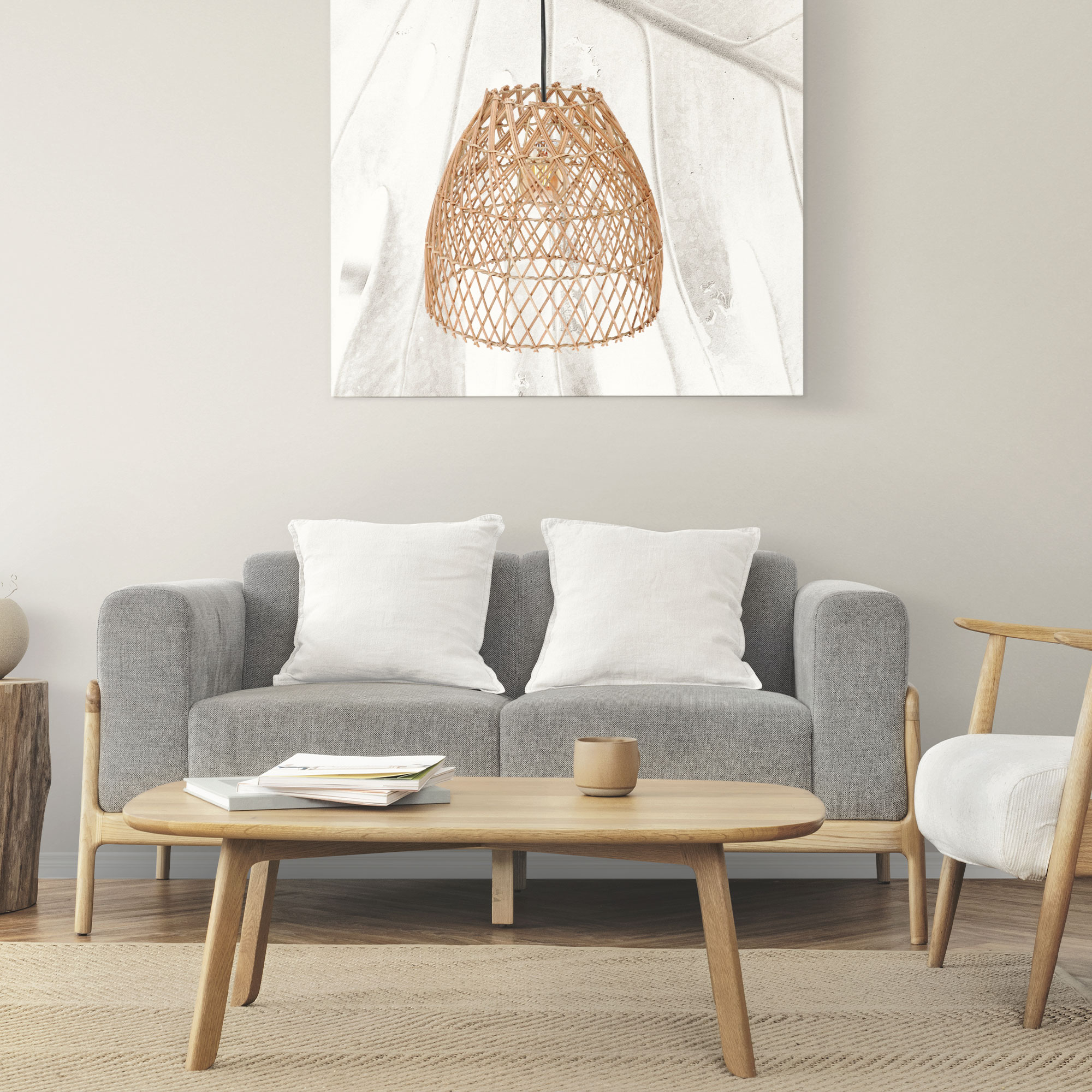 Un sofá gris con cojines blancos se sienta ante una mesa de madera con libros.