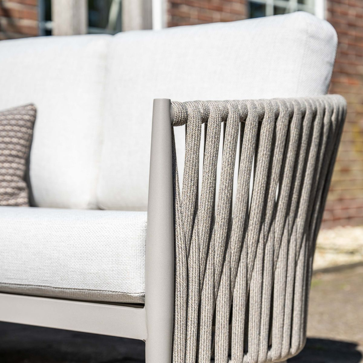 Grijze loungeset met touw rugleuning en witte kussens.