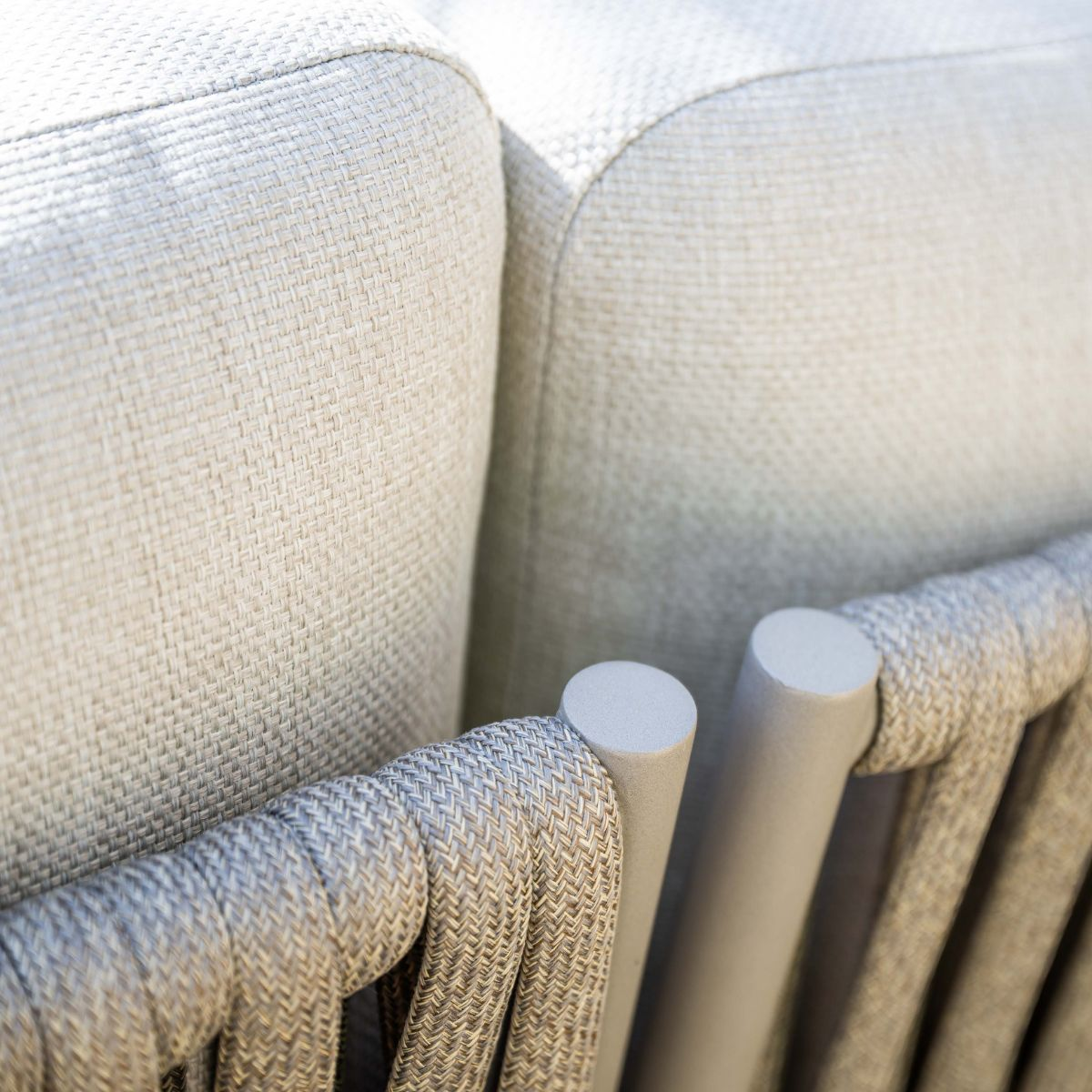 Gray rope weave frames cream cushions on a sofa.