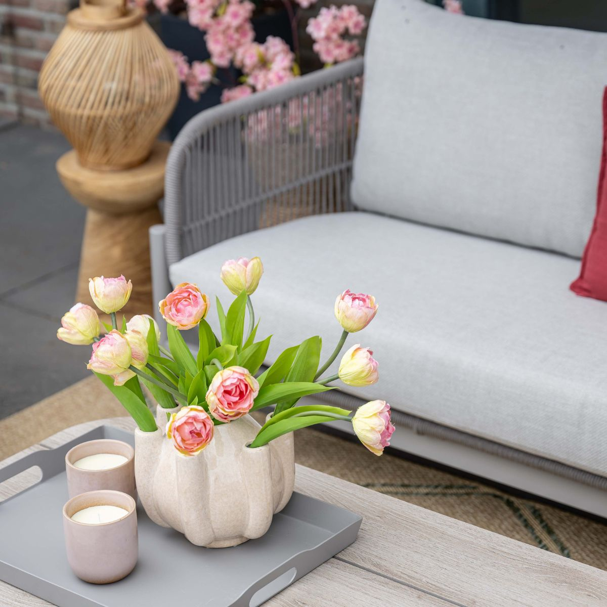 A bouquet of pink and yellow tulips in a vase on a tray.