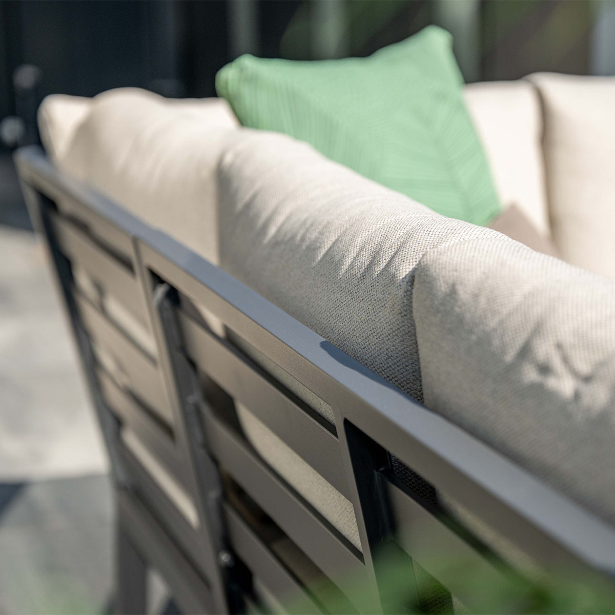 Gray outdoor sofa with cream and green cushions. Close-up view.
