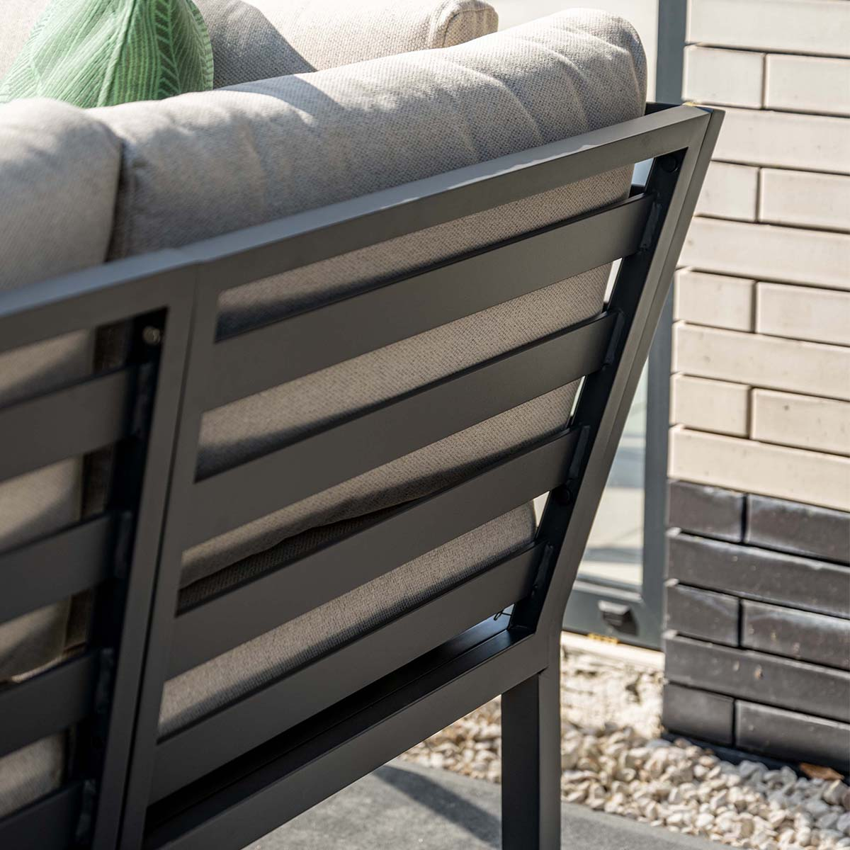 Grey outdoor sofa with slatted back and cushions.
