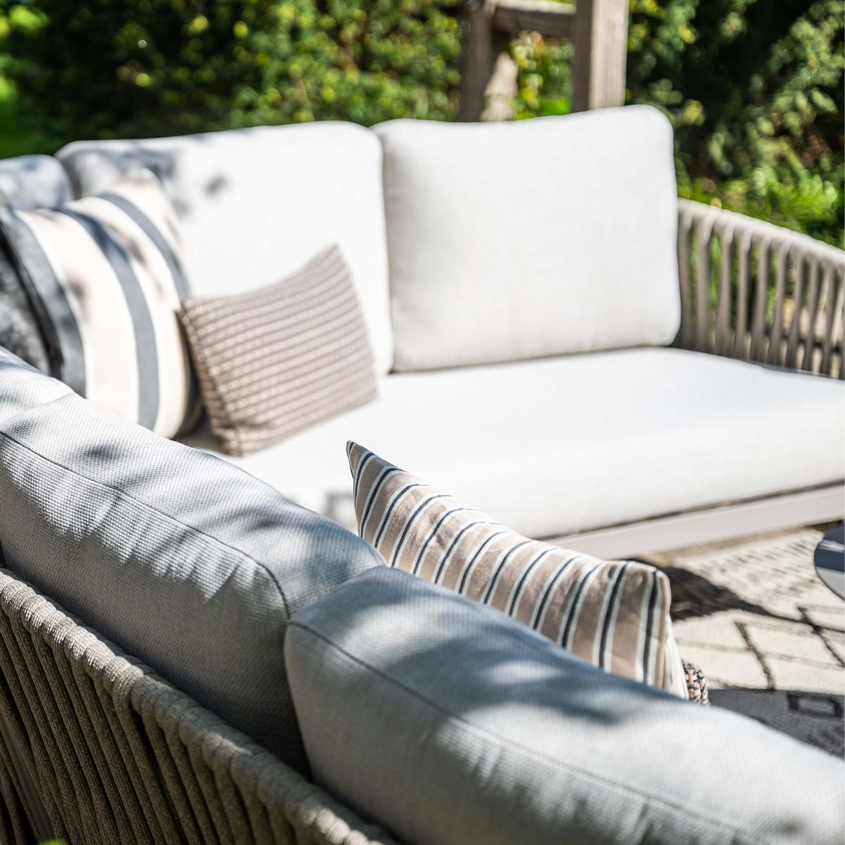 A comfortable outdoor sofa with white and striped cushions in a garden.