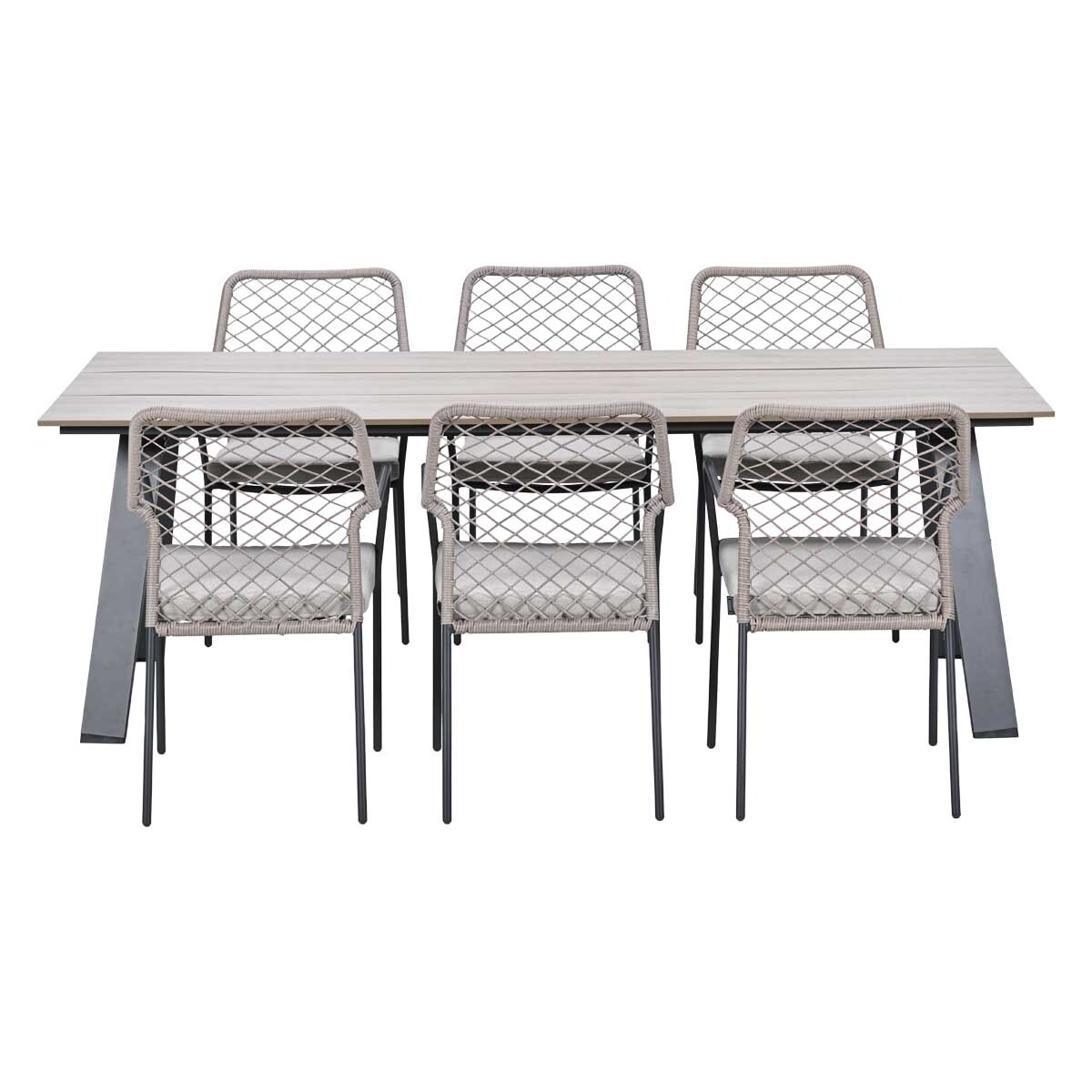 A wooden table with six chairs featuring wicker seats and grey cushions.
