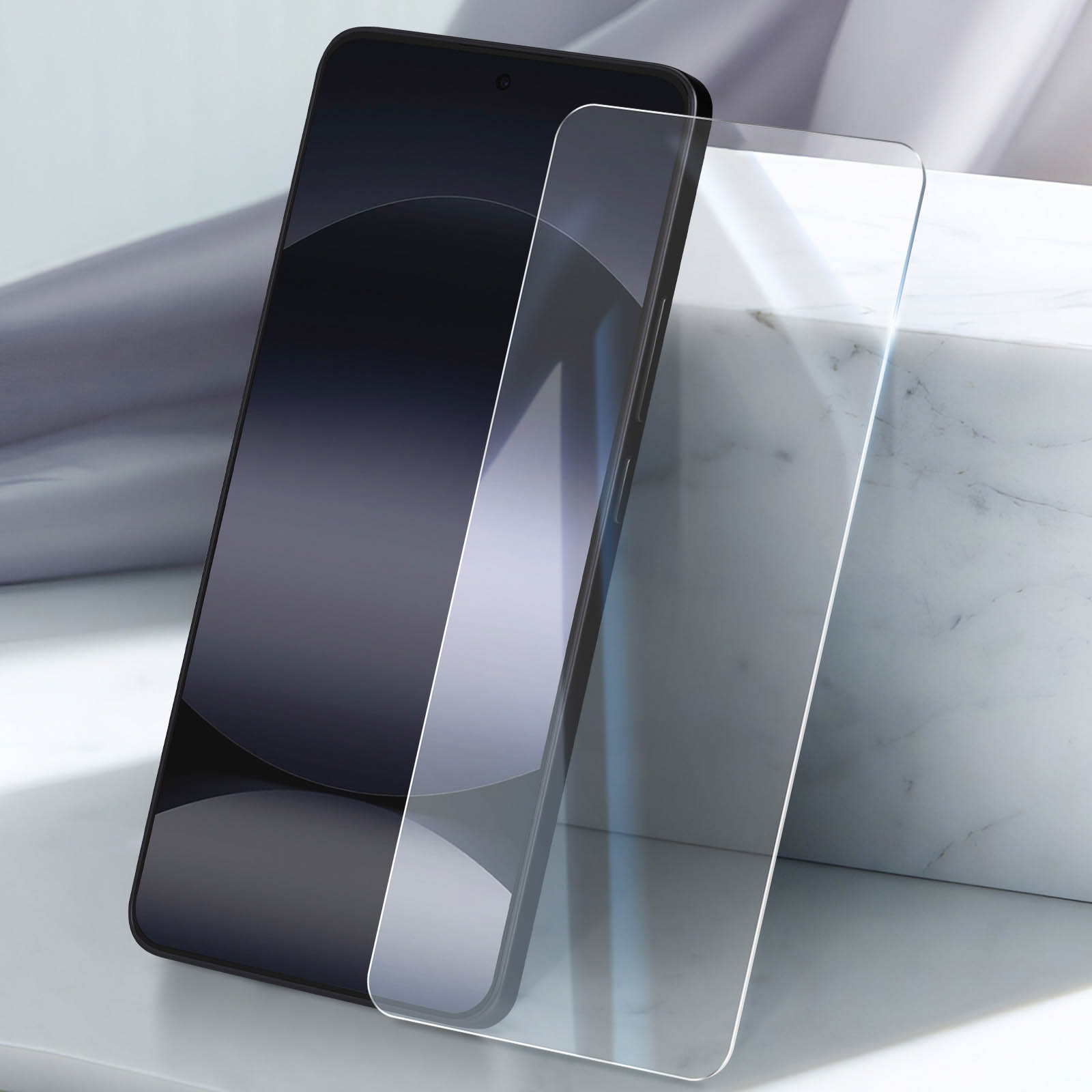 Uno smartphone scuro giace accanto a una protezione per lo schermo trasparente su marmo.
