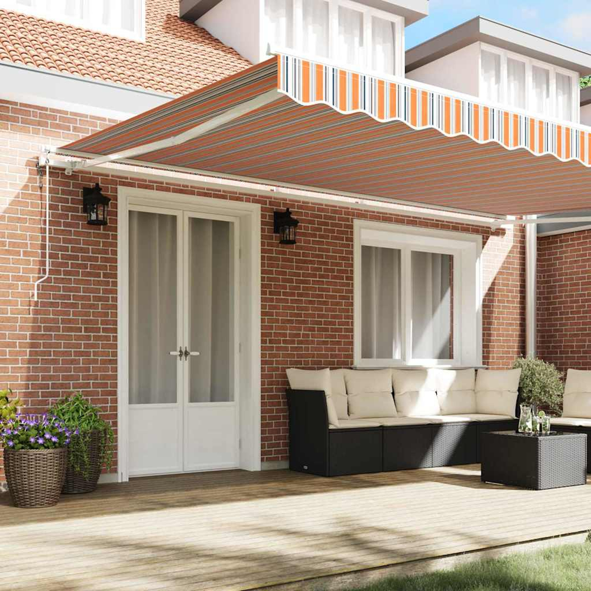 Ein ausziehbarer Sonnenschutz mit orange-grauen Streifen bedeckt eine Terrasse mit Möbeln.