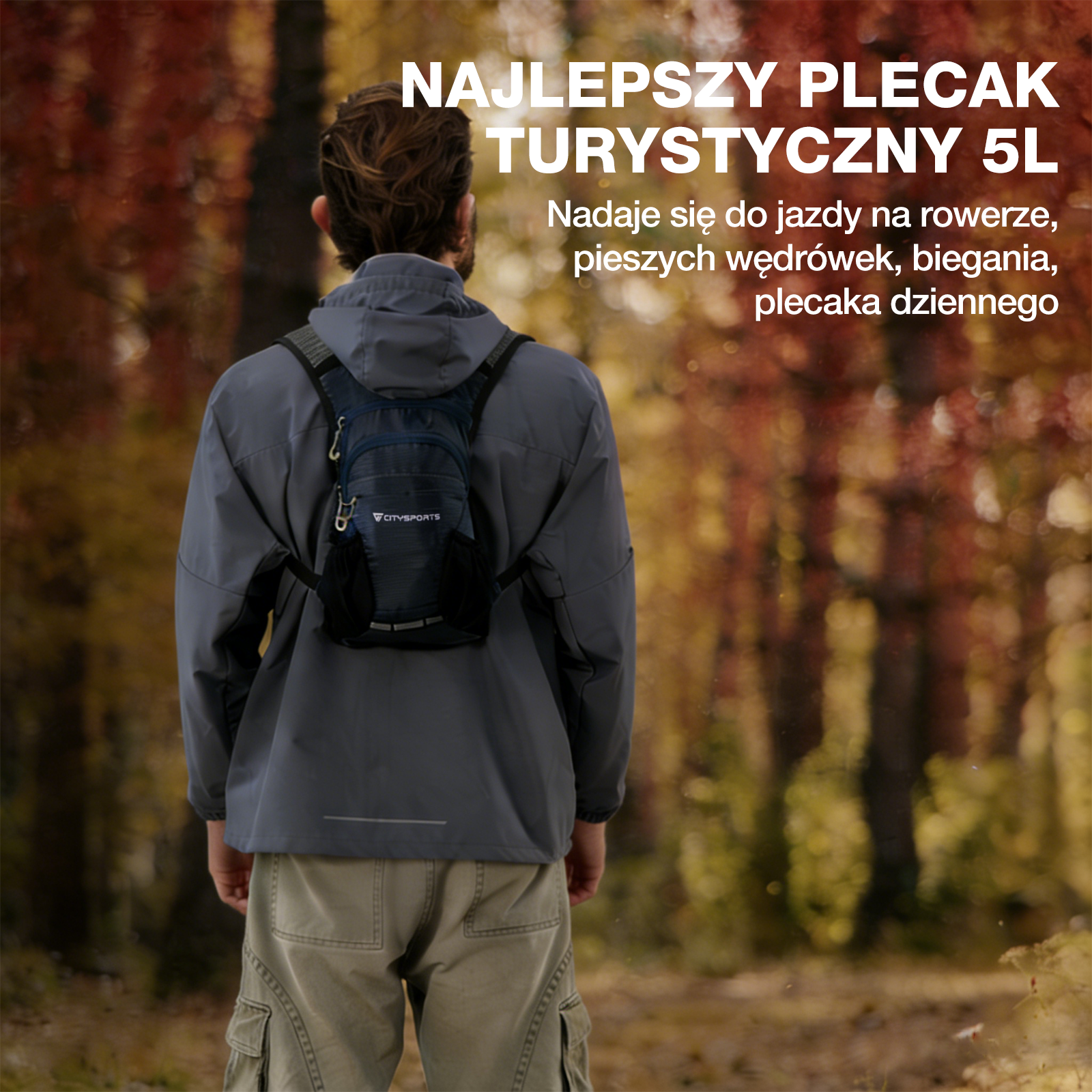 Osoba w szarej kurtce i spodniach cargo nosi mały granatowy plecak, oddalając się w lesie z jesiennym listowiem.