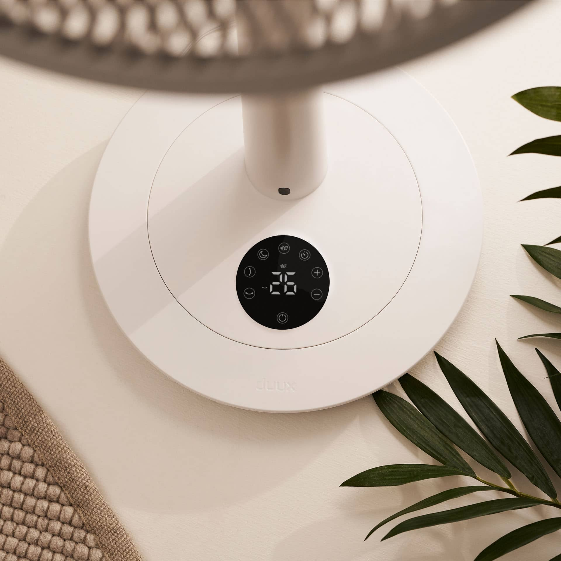 Ein weißer Ventilatorfuß mit schwarzem Touchscreen-Display und grünen Blättern.