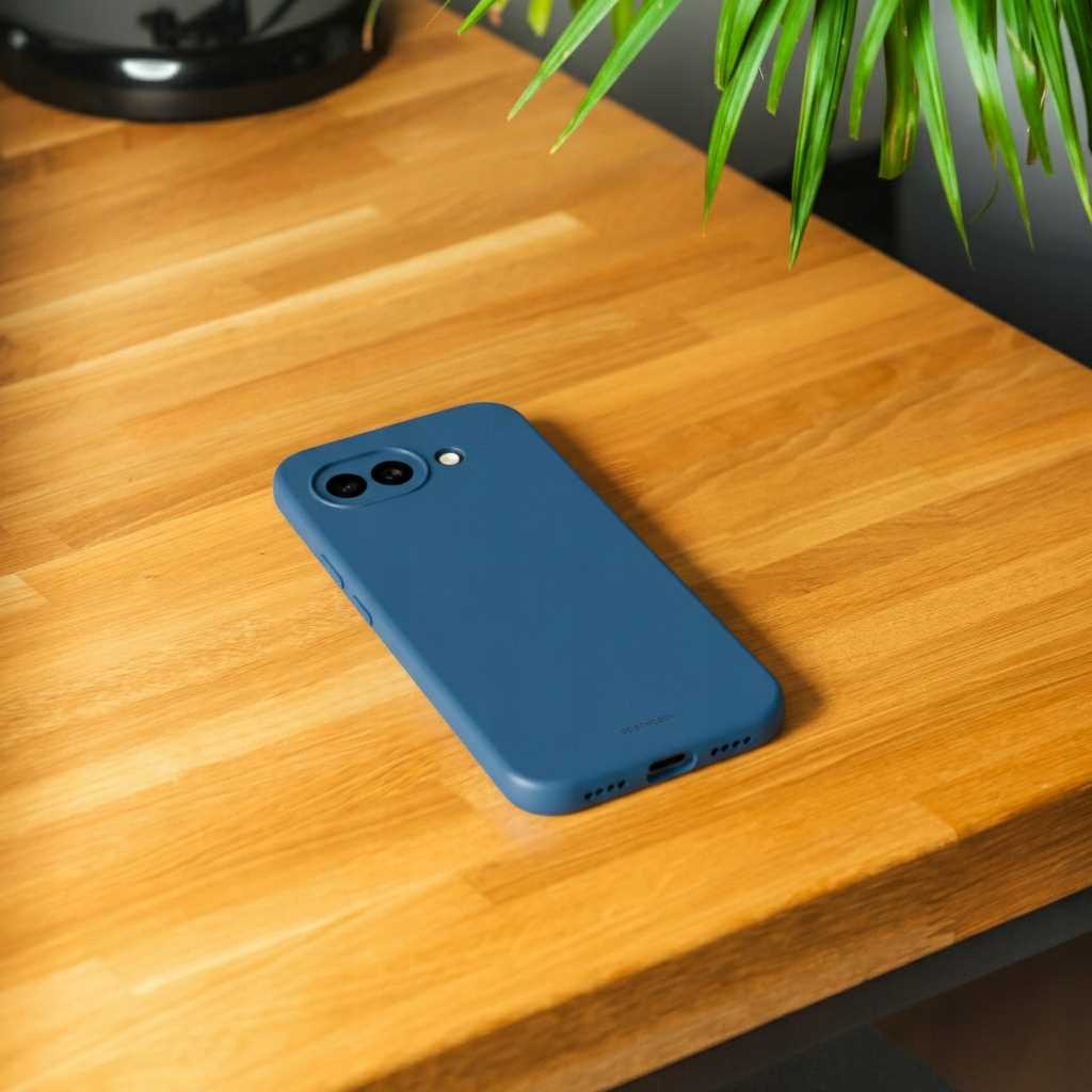 Niebieskie etui na telefon leży na drewnianym stole. Zieleń w tle.