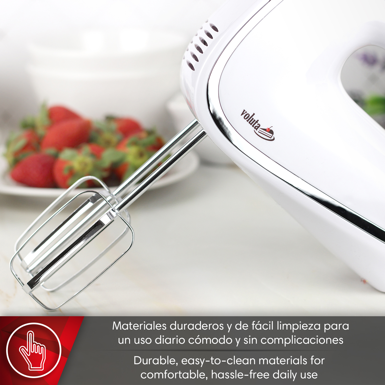 Un batidora de mano blanca con varillas al lado de fresas en un plato.