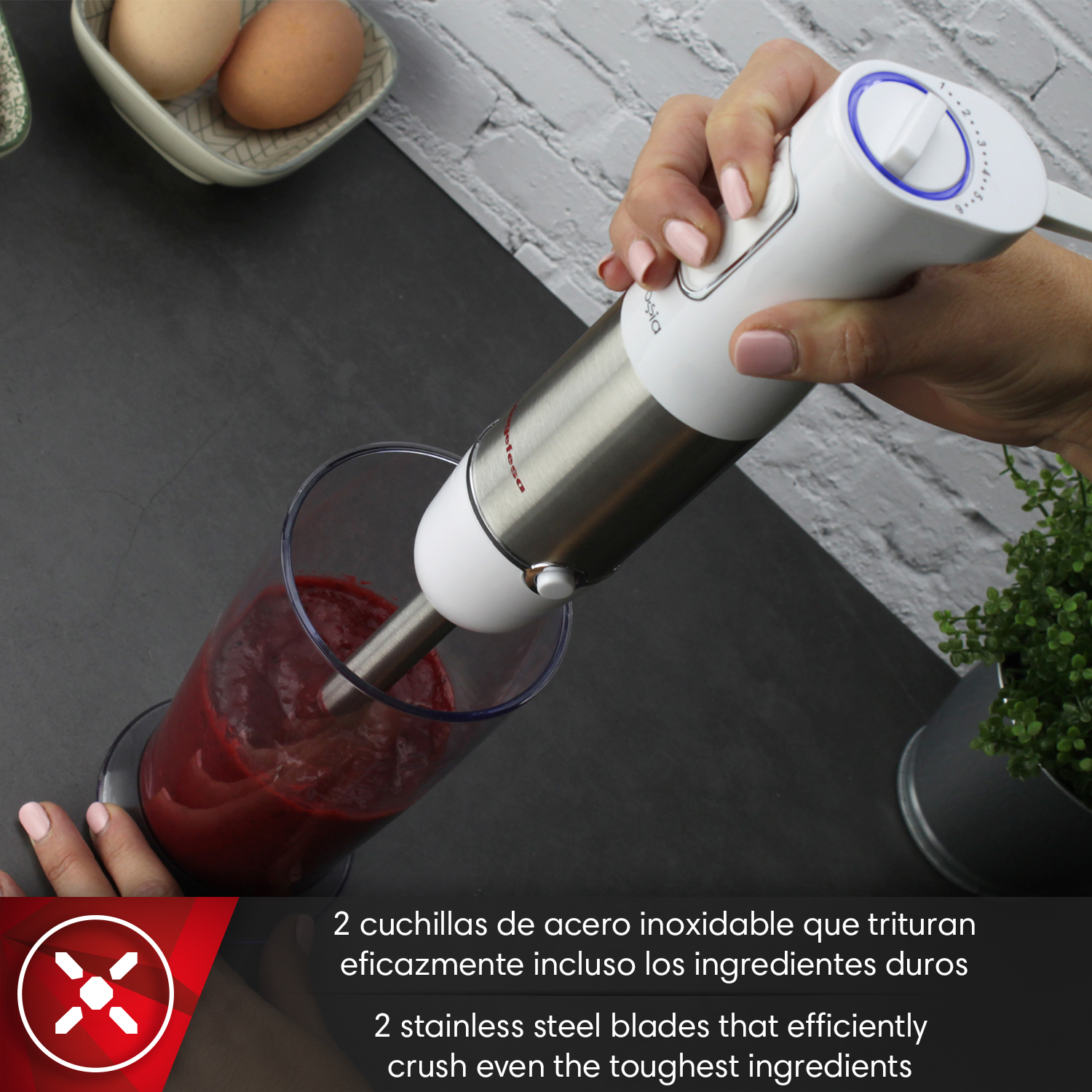 Una mano sostiene una batidora de inmersión mezclando líquido rojo en un vaso.