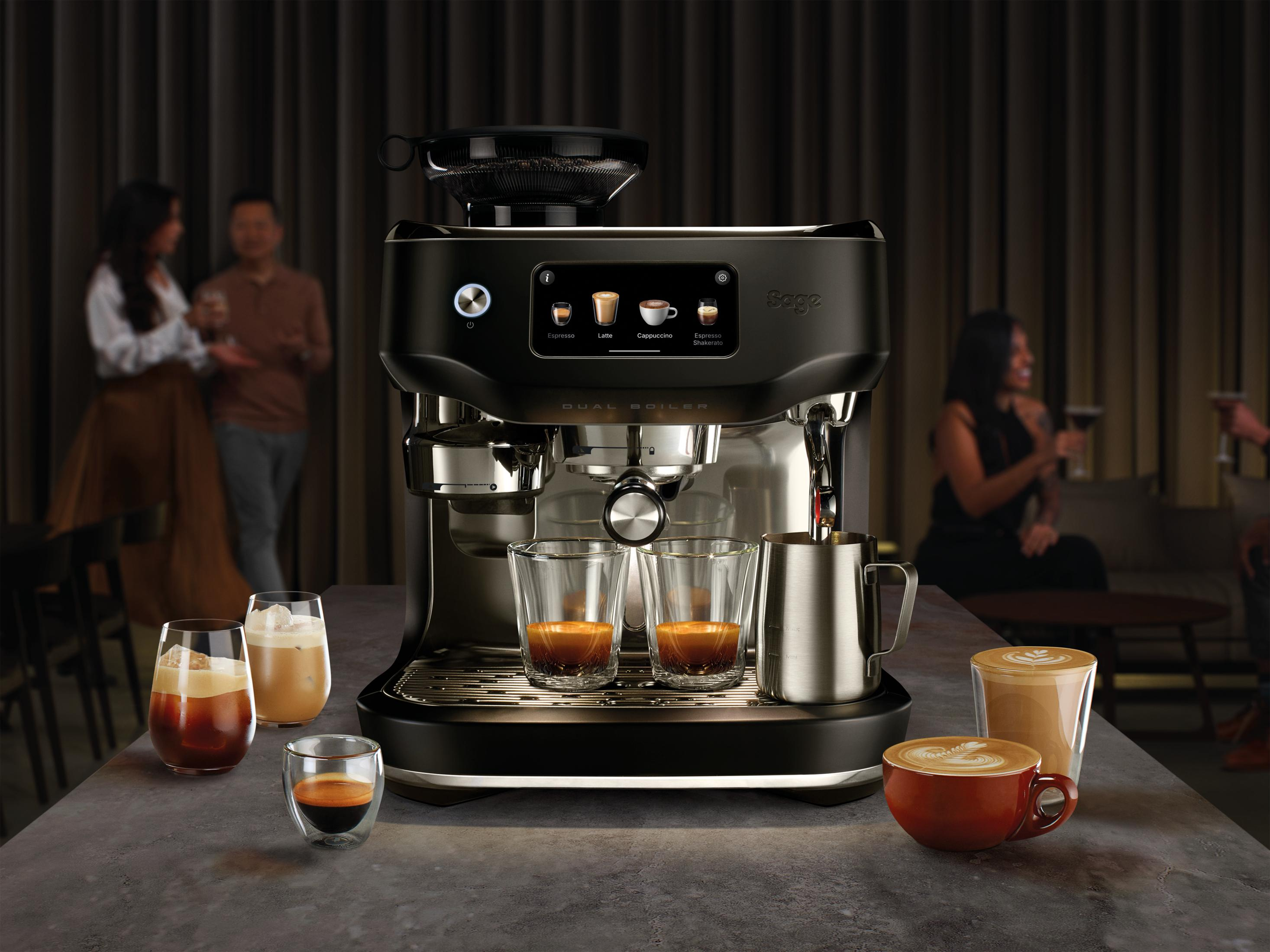 Una macchina per espresso nera con due bicchieri di espresso e un montalatte accanto.