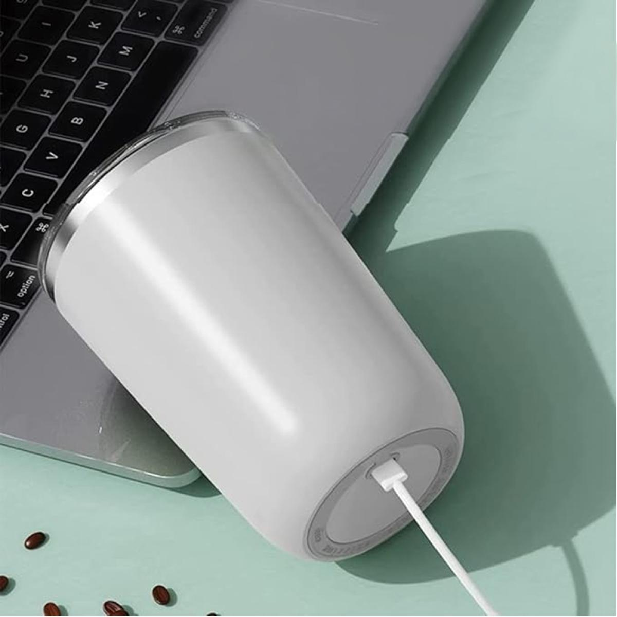A white tumbler with a charging cable rests on a keyboard with a mint green background.