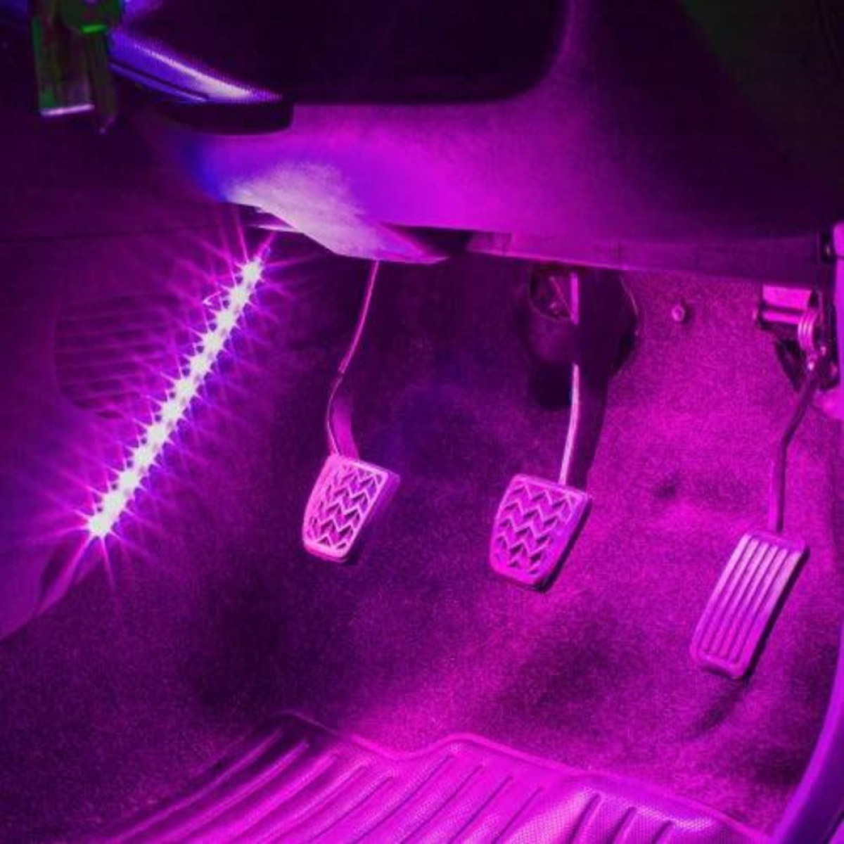 Paarse interieurverlichting verlicht drie pedalen en de autobekleding.