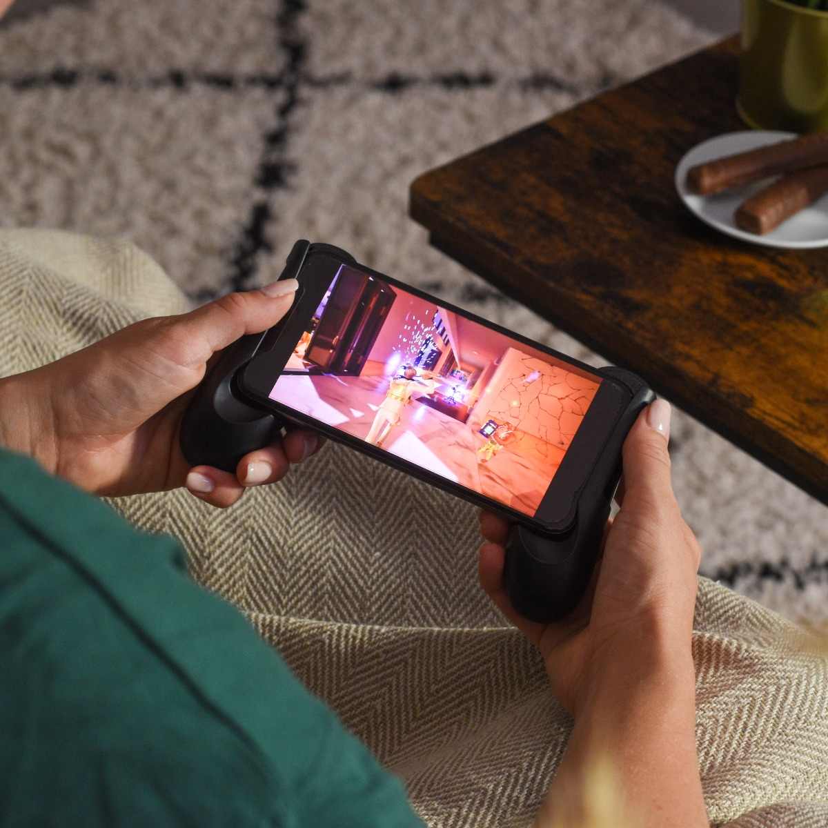 Persoon speelt mobiele game met controller grip. Close-up van handen.