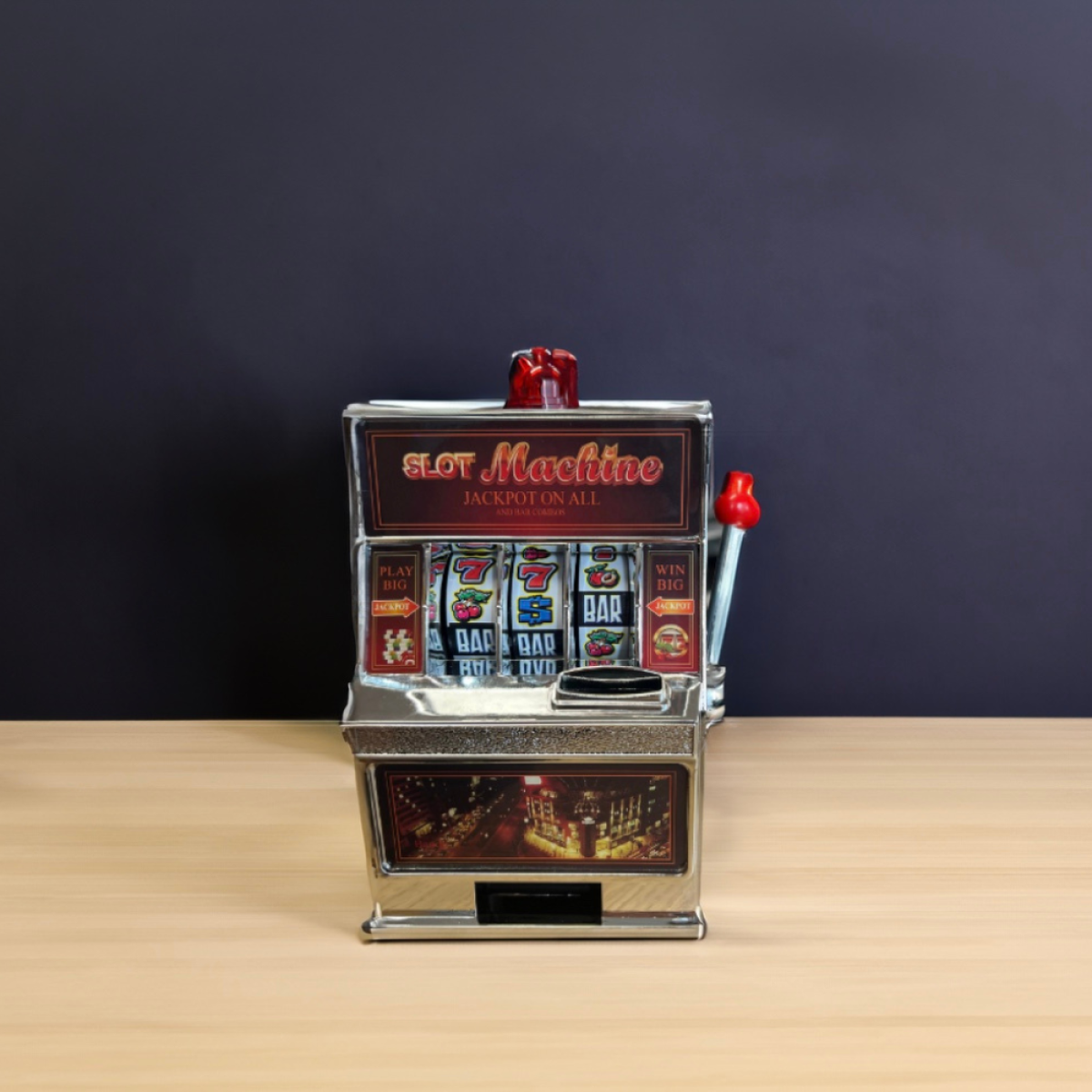 Een zilverkleurige gokautomaat met rode hendels, op een houten tafel.